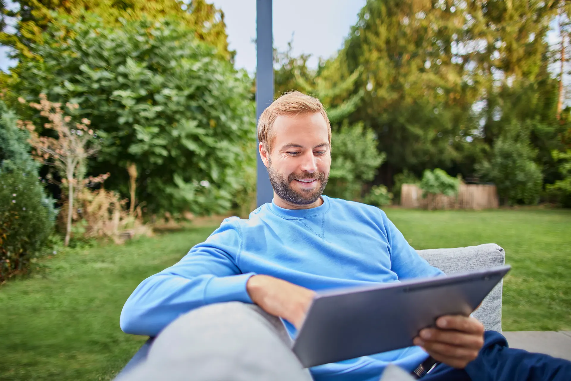 Ein Mann informiert sich über verschiedene Themen Ein Mann sitzt im Garten mit einem Tablet und informiert sich über die Tarife der NEW Energie.
