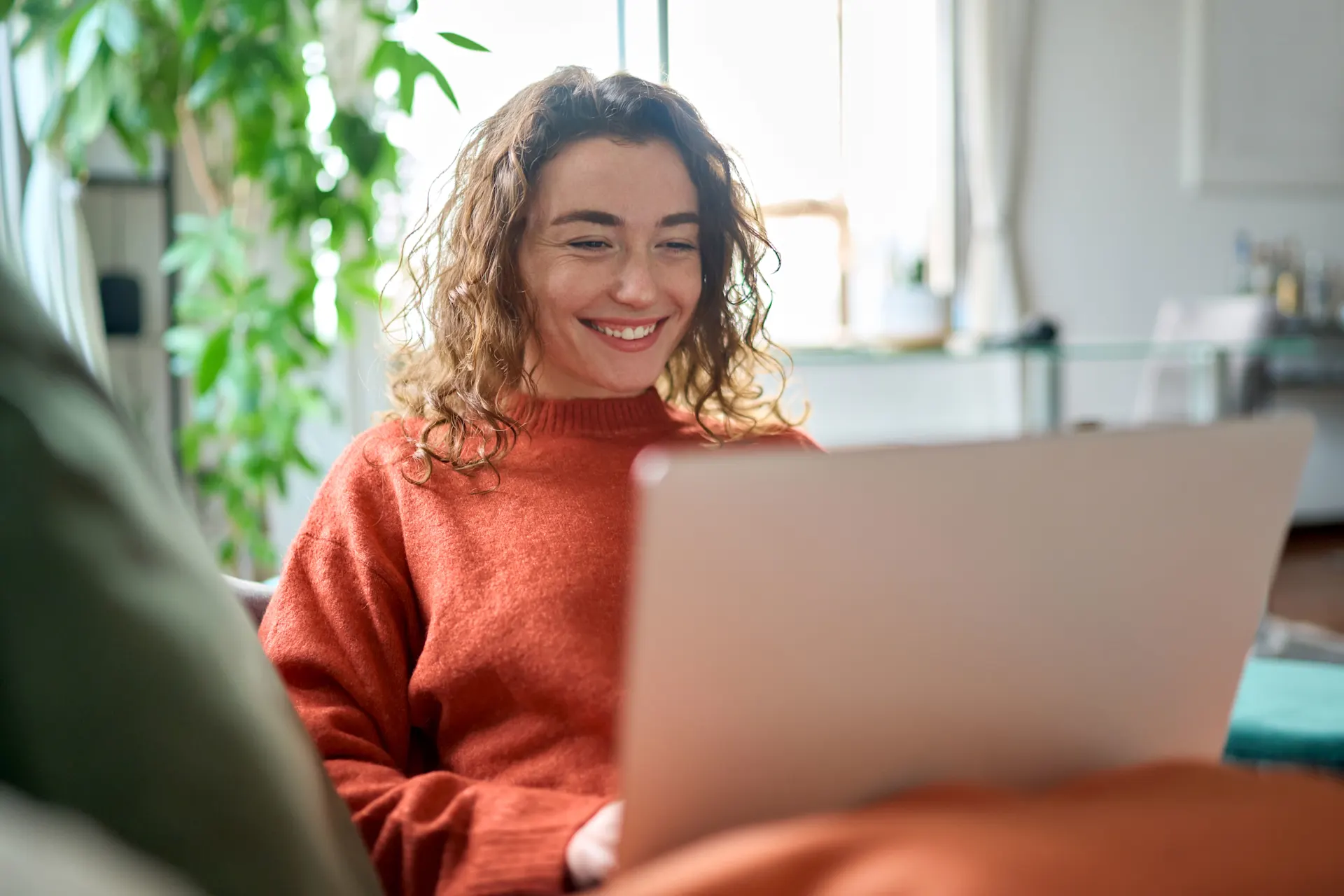 Studentin prueft die Angebote der NEW Energie Studentin sitzt mit einem Laptop auf dem Sofa.