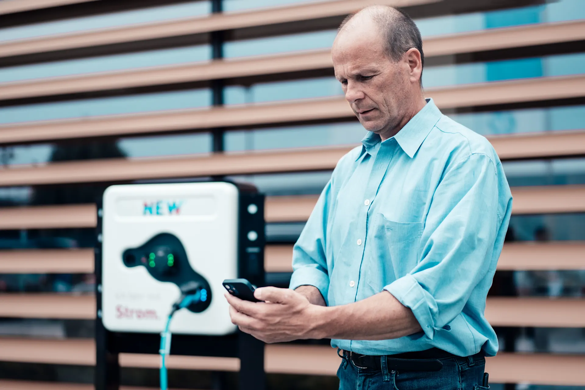 Ladestation für Elektromobilität Ein Mann schaut auf sein Handy vor einer Ladestation für Elektromobilität der NEW Energie.