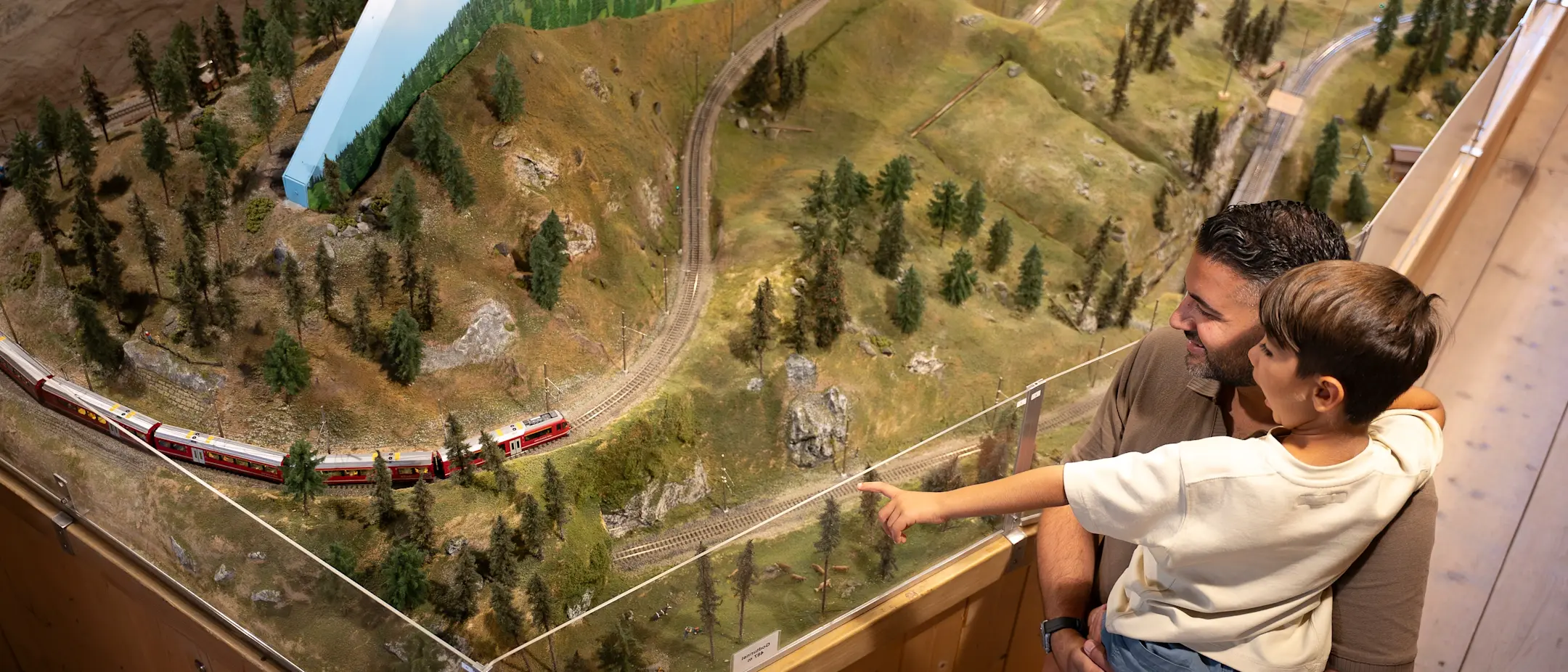 Vater und Sohn schauen im Ortsmuseum Bergün auf eine Modelleisenbahn