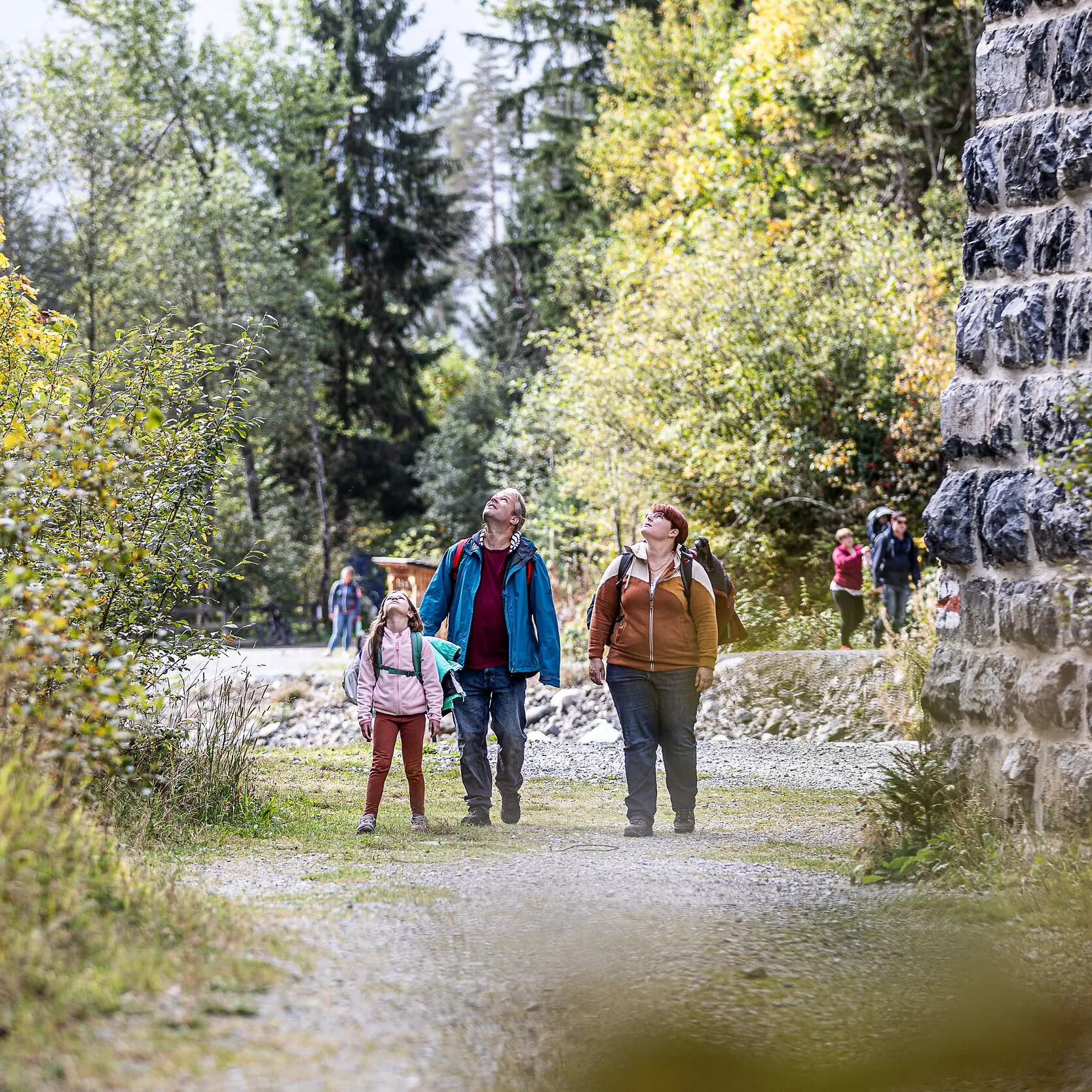 Drei Personen in Wanderkleidung schauen am Pfeiler des Landviaduktes hoch.