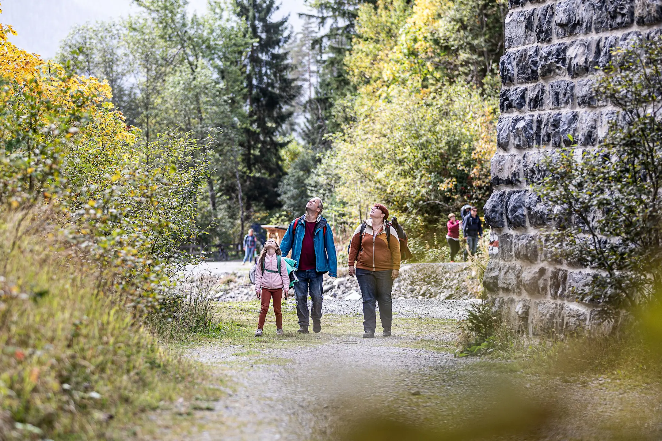 Drei Personen in Wanderkleidung schauen am Pfeiler des Landviaduktes hoch.