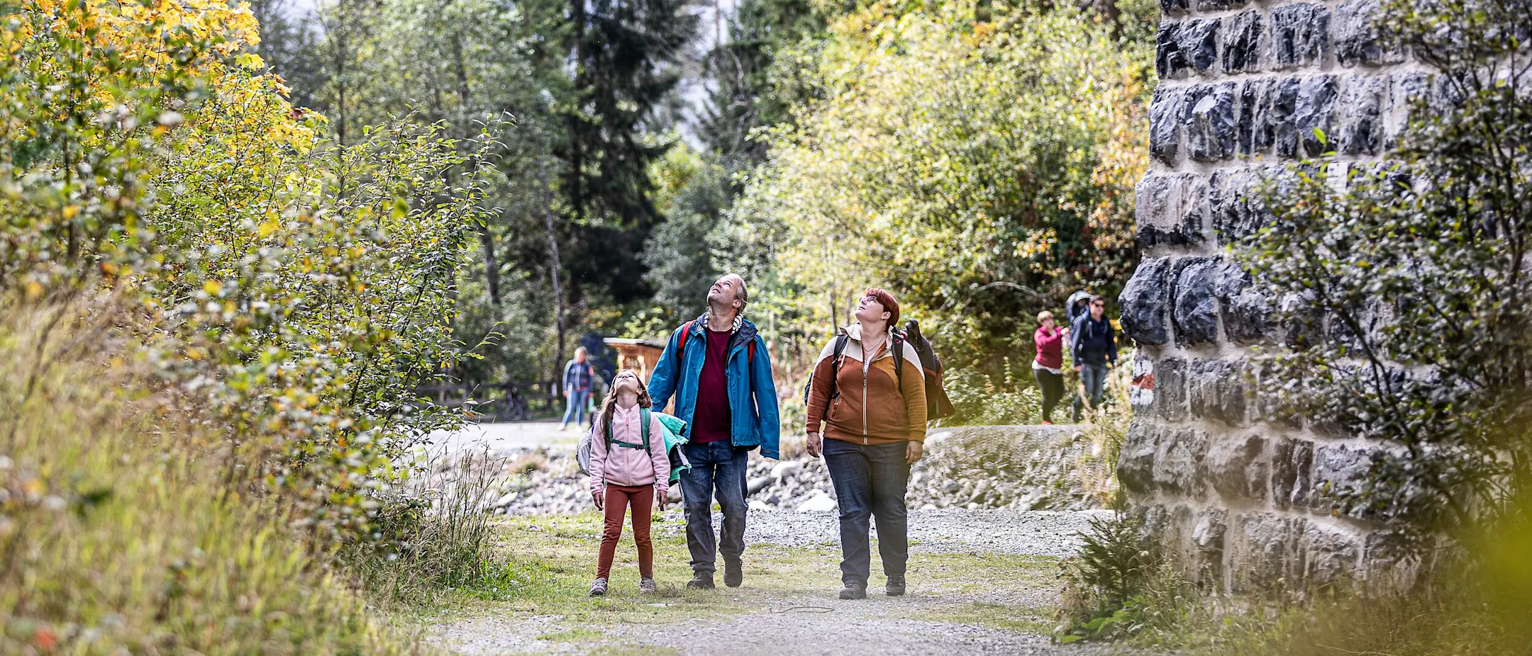 Drei Personen in Wanderkleidung schauen am Pfeiler des Landviaduktes hoch.