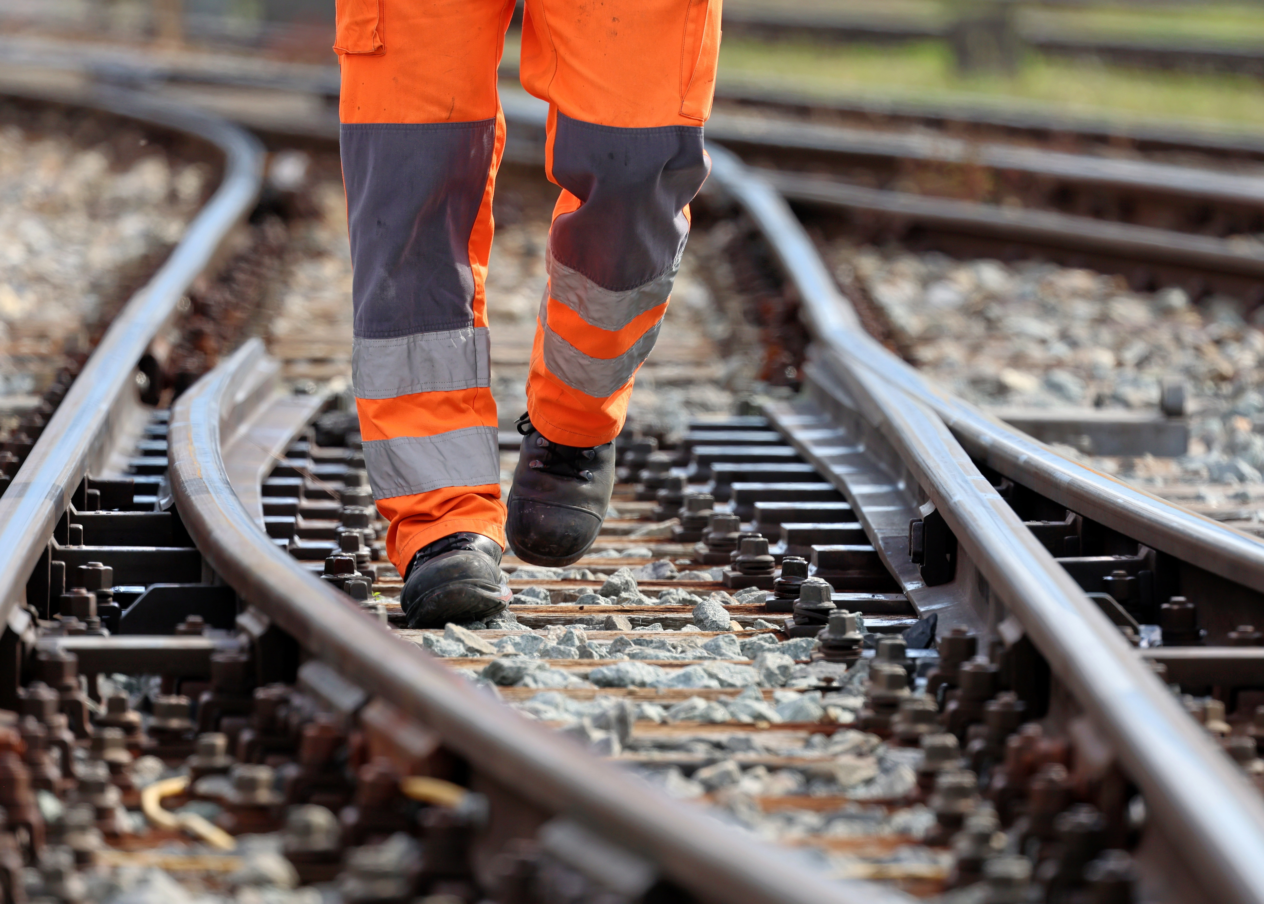 Ein Mitarbeiter der RhB in orangener Warnkleidung läuft durch eine Weiche
