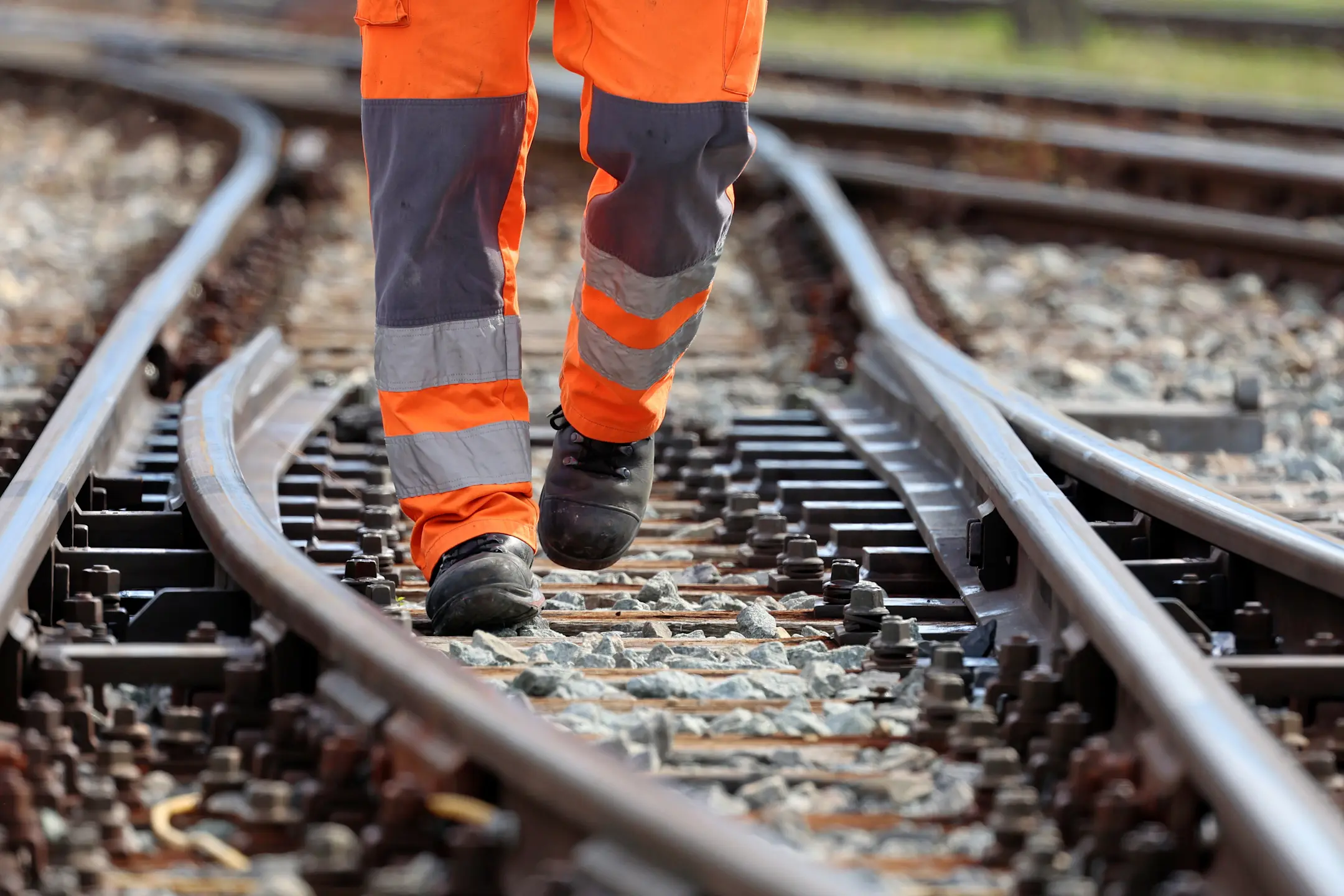 Ein Mitarbeiter der RhB in orangener Warnkleidung läuft durch eine Weiche