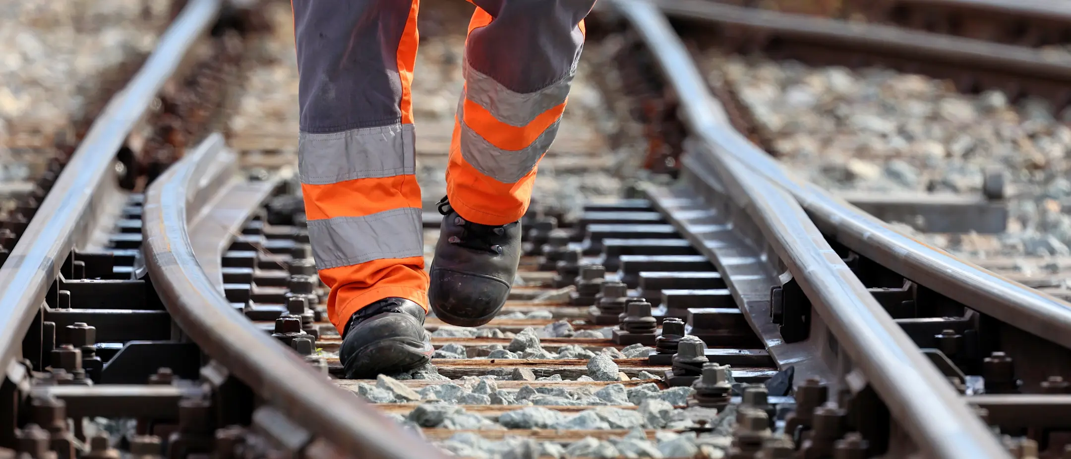 Ein Mitarbeiter der RhB in orangener Warnkleidung läuft durch eine Weiche