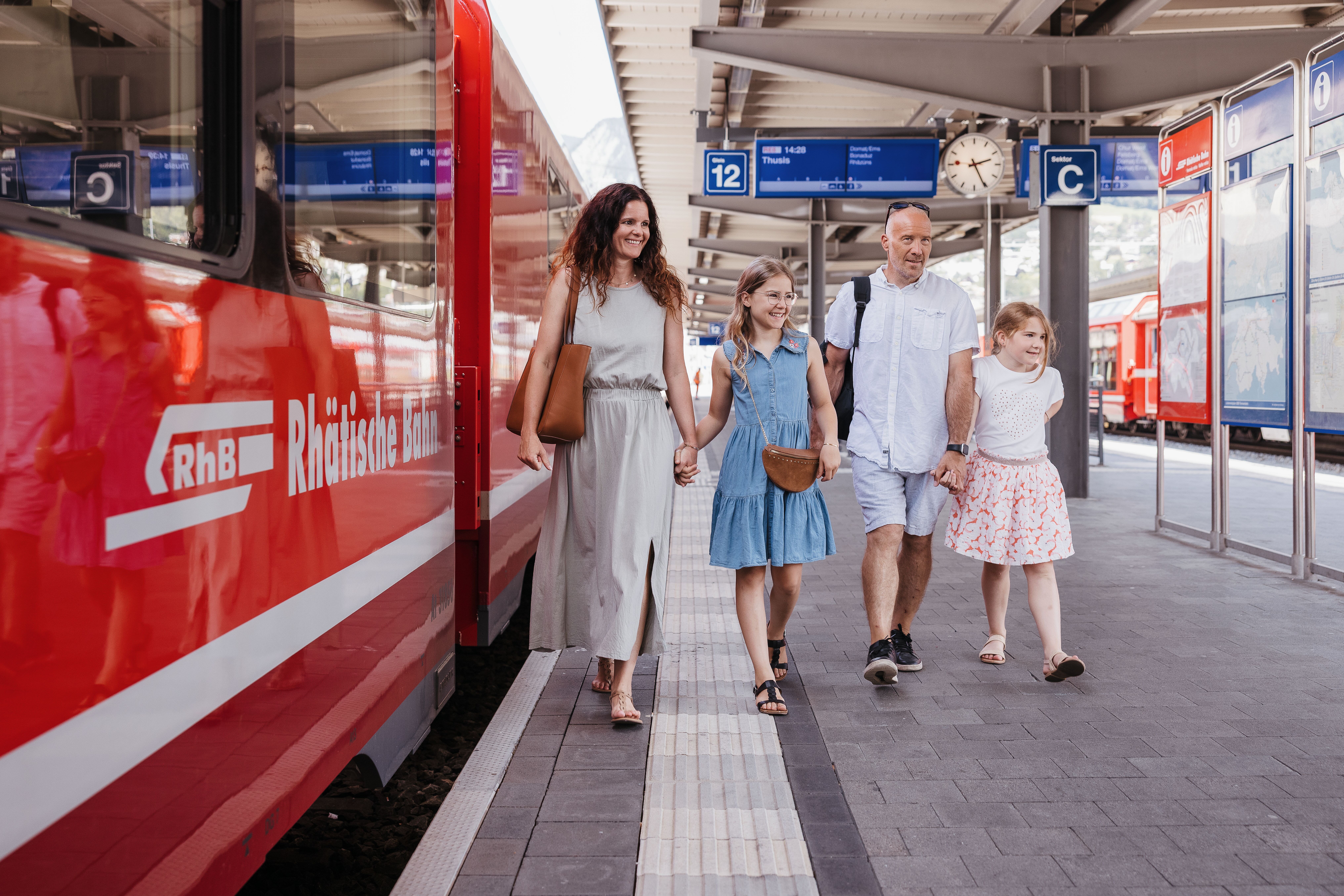 Eine Familie läuft am Perron entlang. 