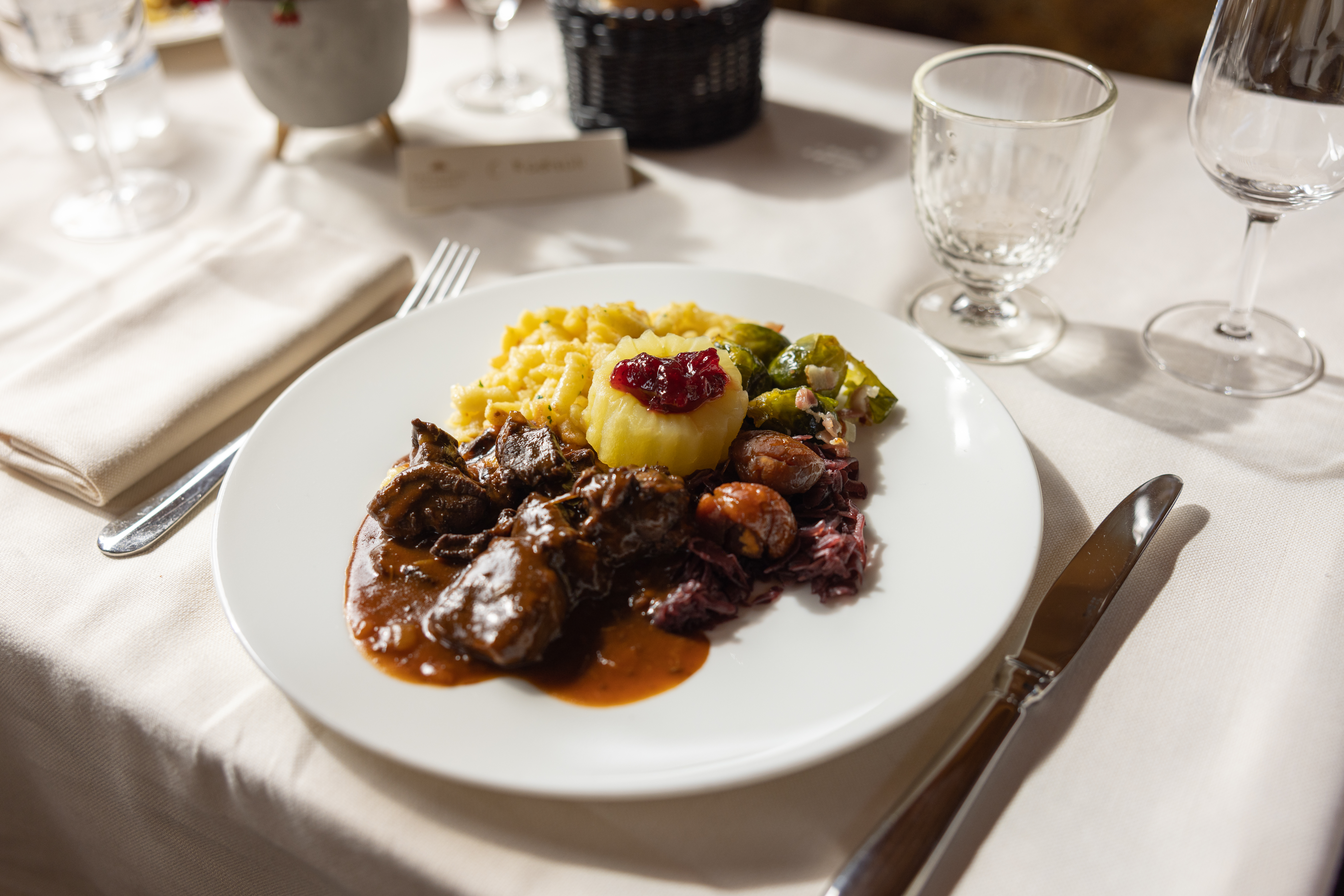 A table laid with white tablecloths, featuring a plate of traditional game specialities.