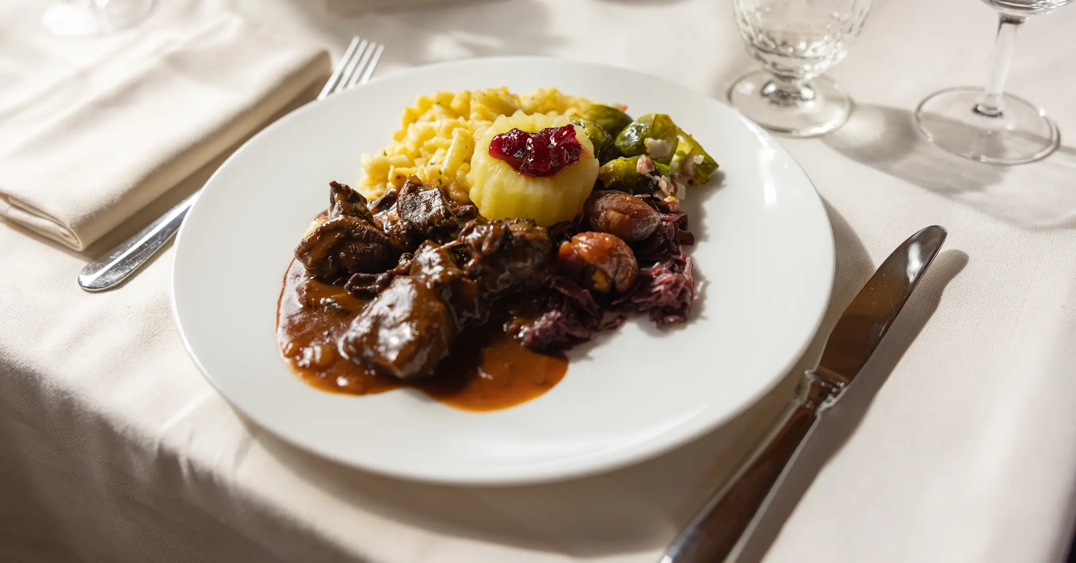 A table laid with white tablecloths, featuring a plate of traditional game specialities.
