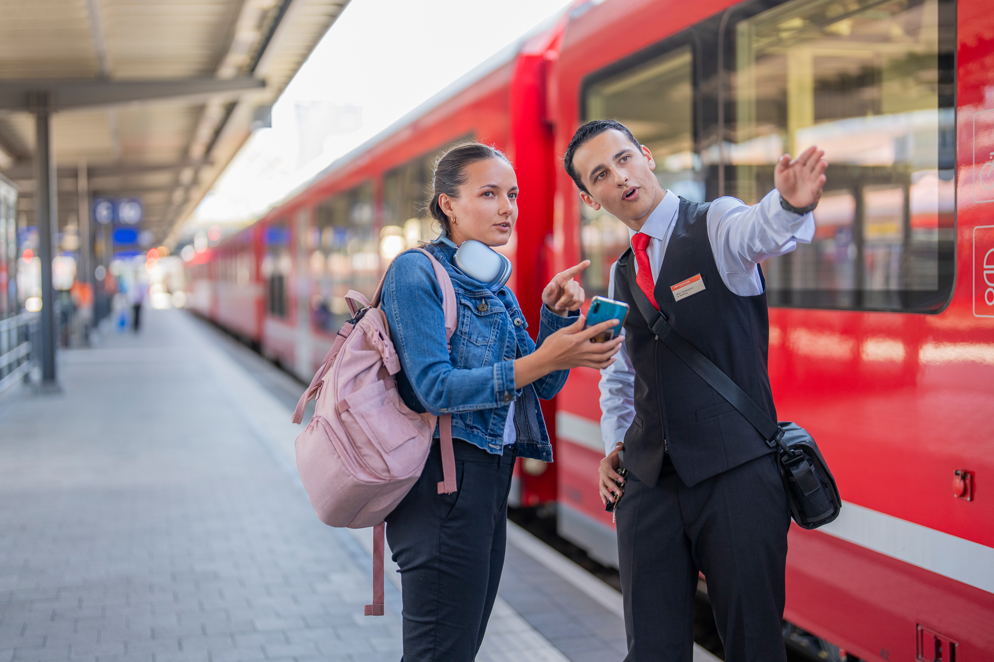 Ein junger Zugbegleiter erklärt Kundin den Weg