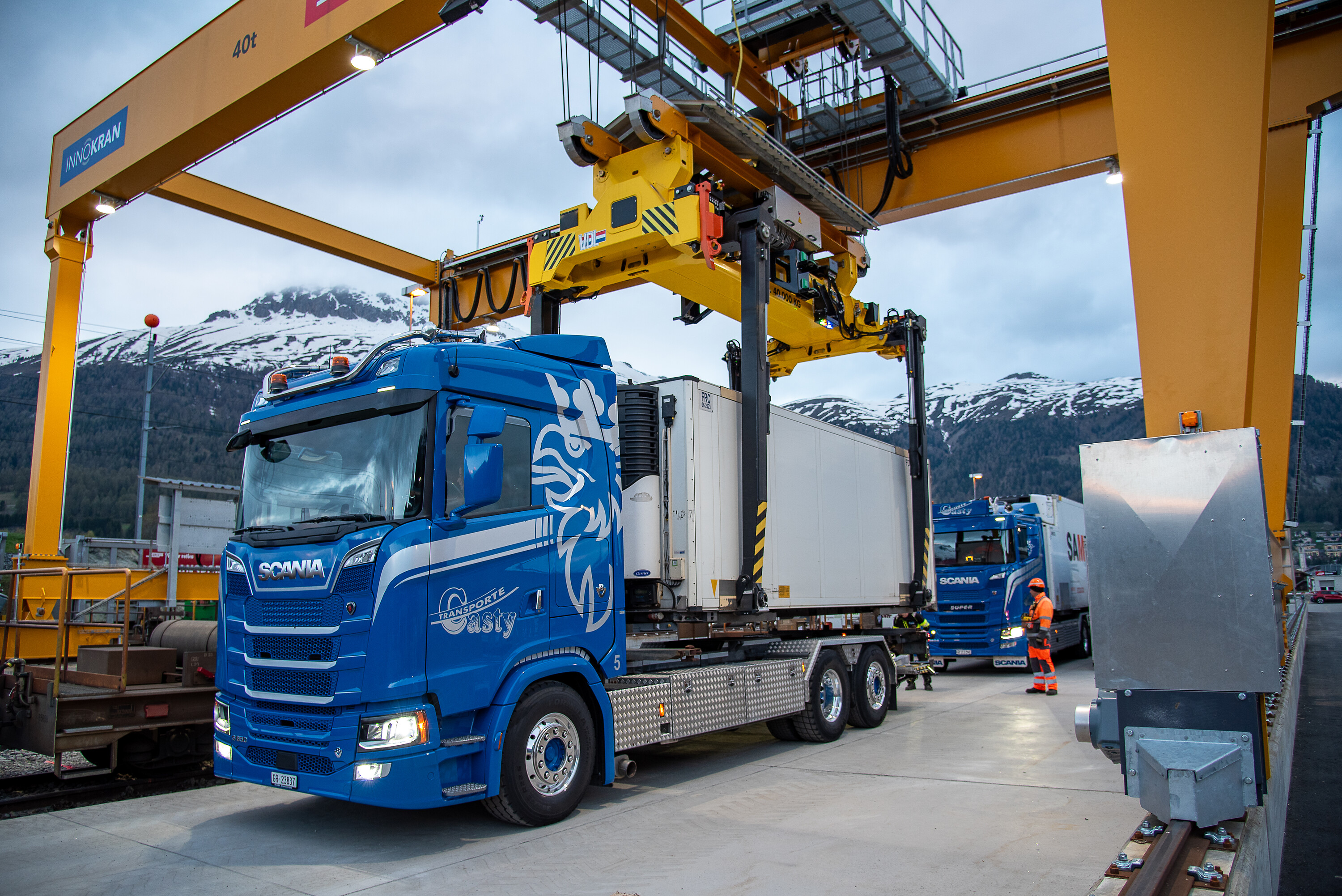 Ein Wechselbehälter der RhB wird an einem GUZ durch eine Krananlage vom LKW auf einen Güterwagen umgeladen