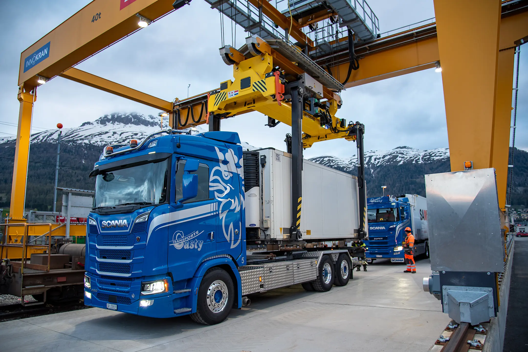 Ein Wechselbehälter der RhB wird an einem GUZ durch eine Krananlage vom LKW auf einen Güterwagen umgeladen