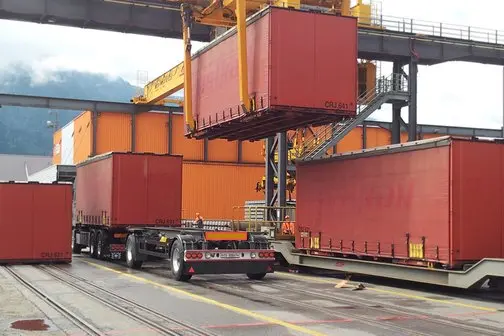 Ein Wechselbehälter der RhB wird an einem GUZ durch eine Krananlage vom LKW auf einen Güterwagen umgeladen