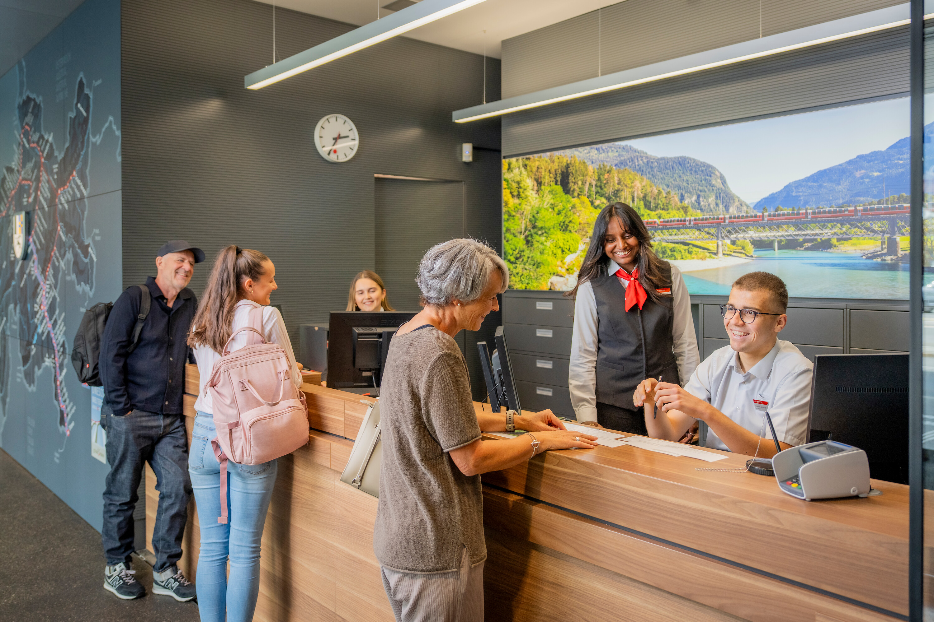 Drei Reiseberaterinnen und -Berater helfen Fahrgästen am Schalter