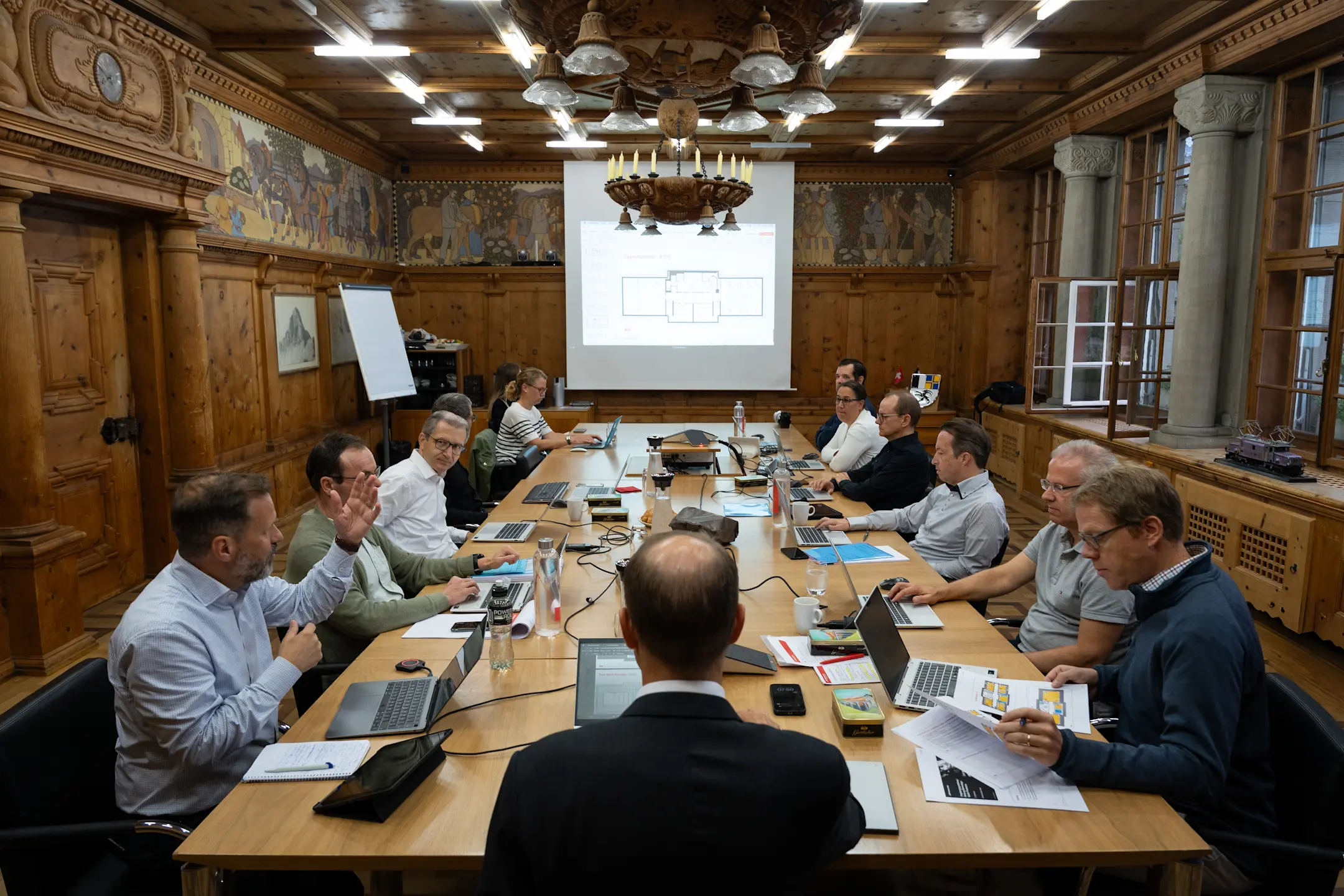 Geschäftsleitungssitzung der RhB: Renato Fasciati sitzt am Kopfende eines langen Tisches im historischen Konferenzraum.