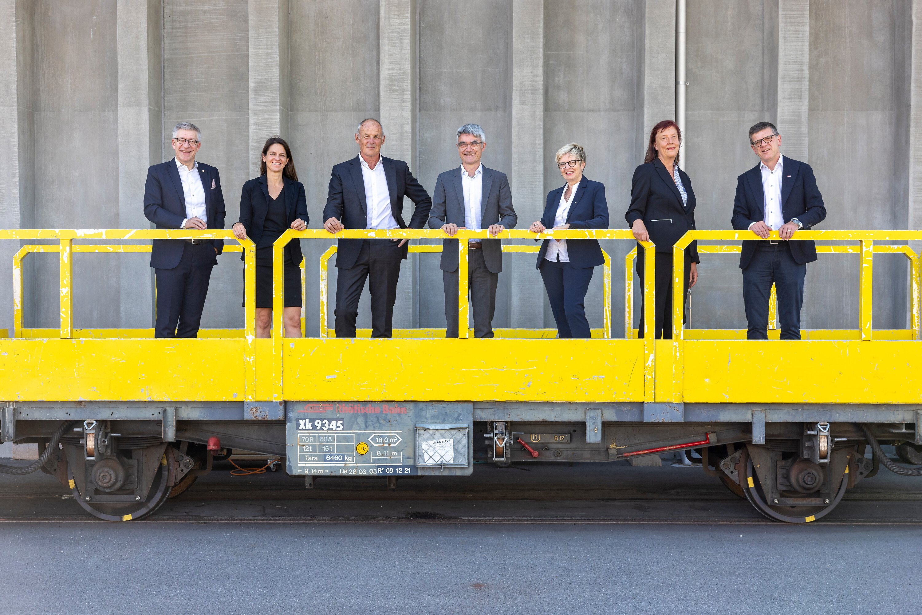 Der Verwaltungsrat der Rhätischen Bahn auf einem gelben Güterwagen