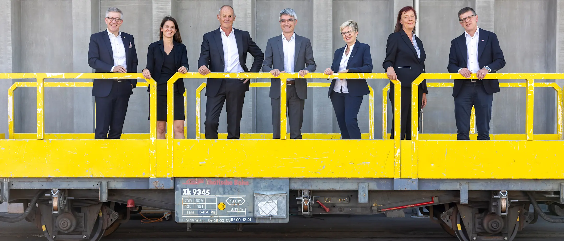 Der Verwaltungsrat der Rhätischen Bahn auf einem gelben Güterwagen