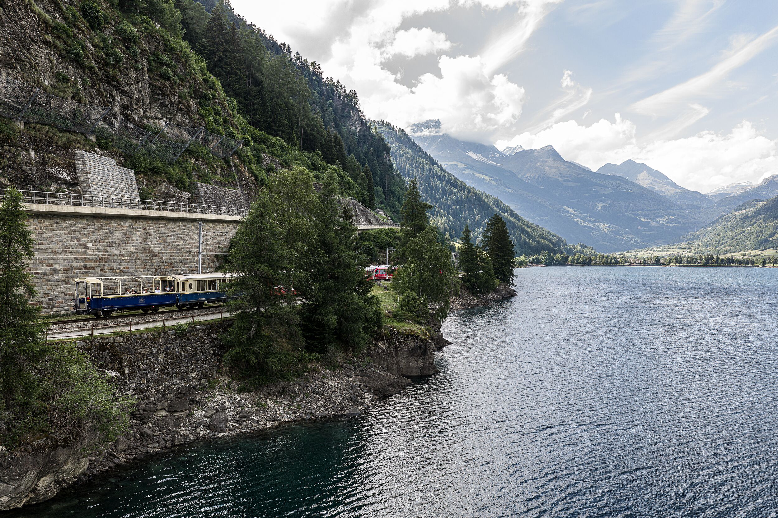 Die Bernina Express Pullman Class fährt am Seeufer entlang. 