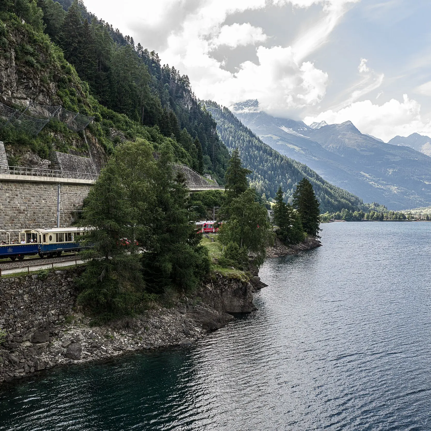 Die Bernina Express Pullman Class fährt am Seeufer entlang.