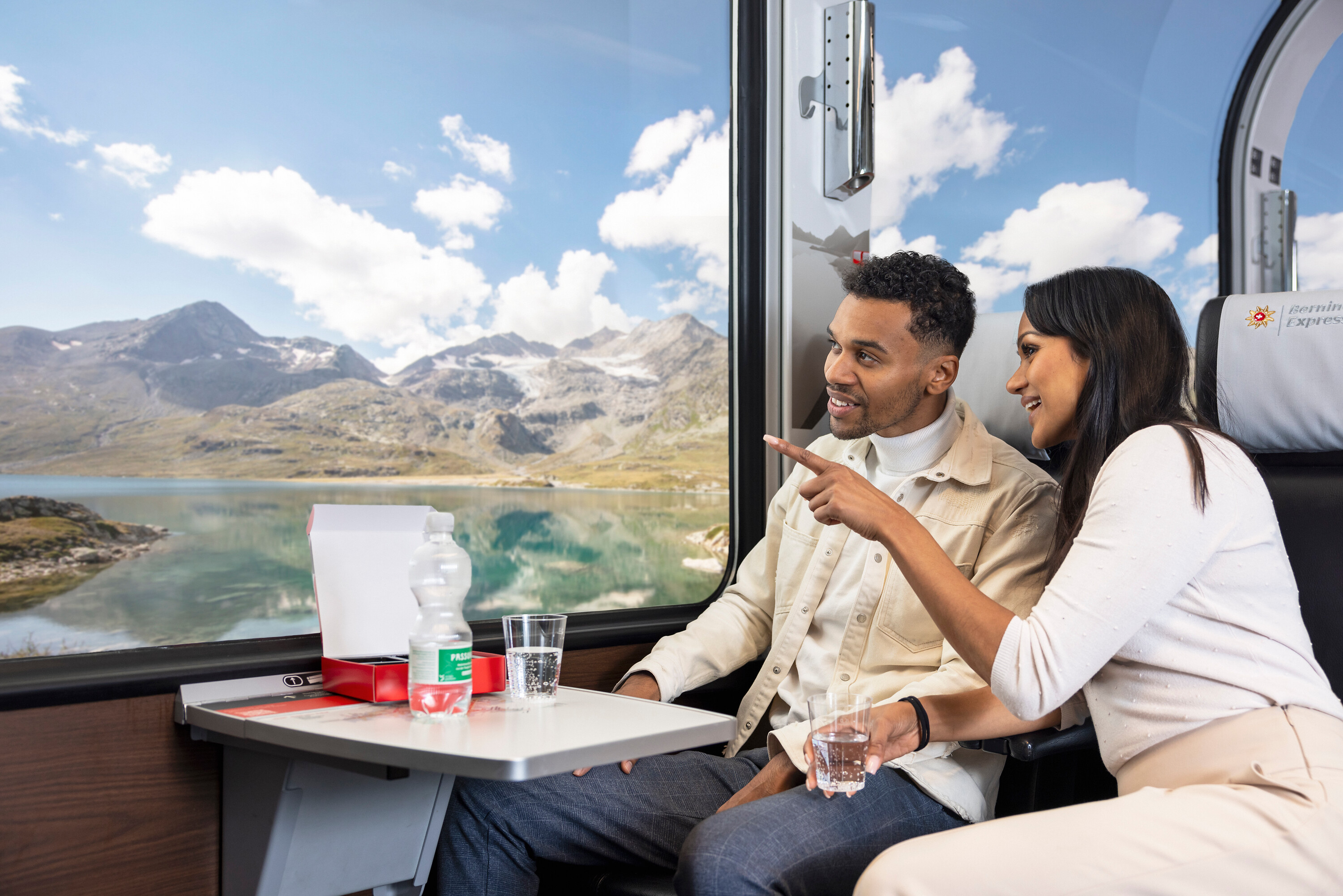 Fahrgäste im Bernina Express bestaunen den Lago Bianco auf dem Berninapass.