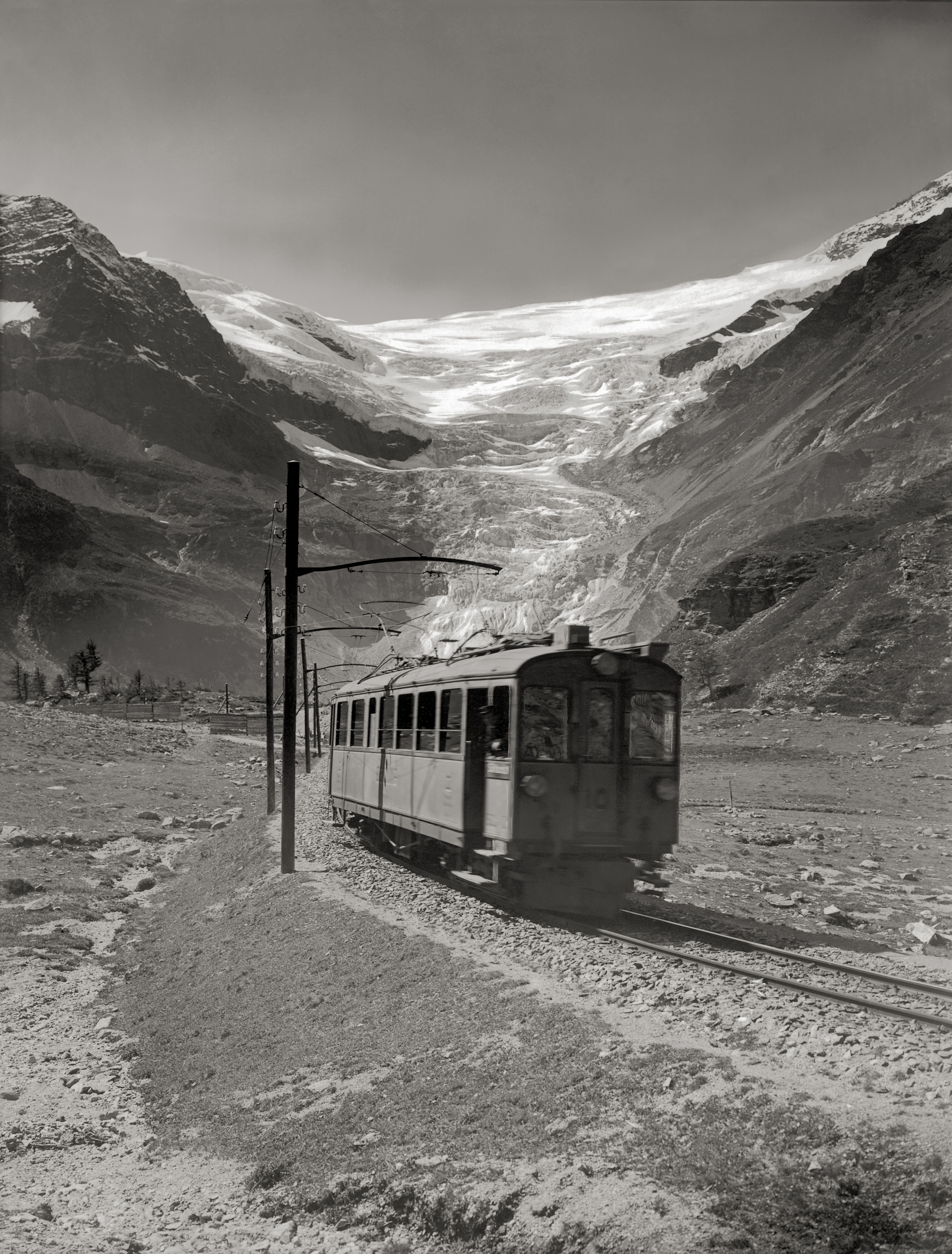 A historic train travels in front of the Palü Glacier in summer