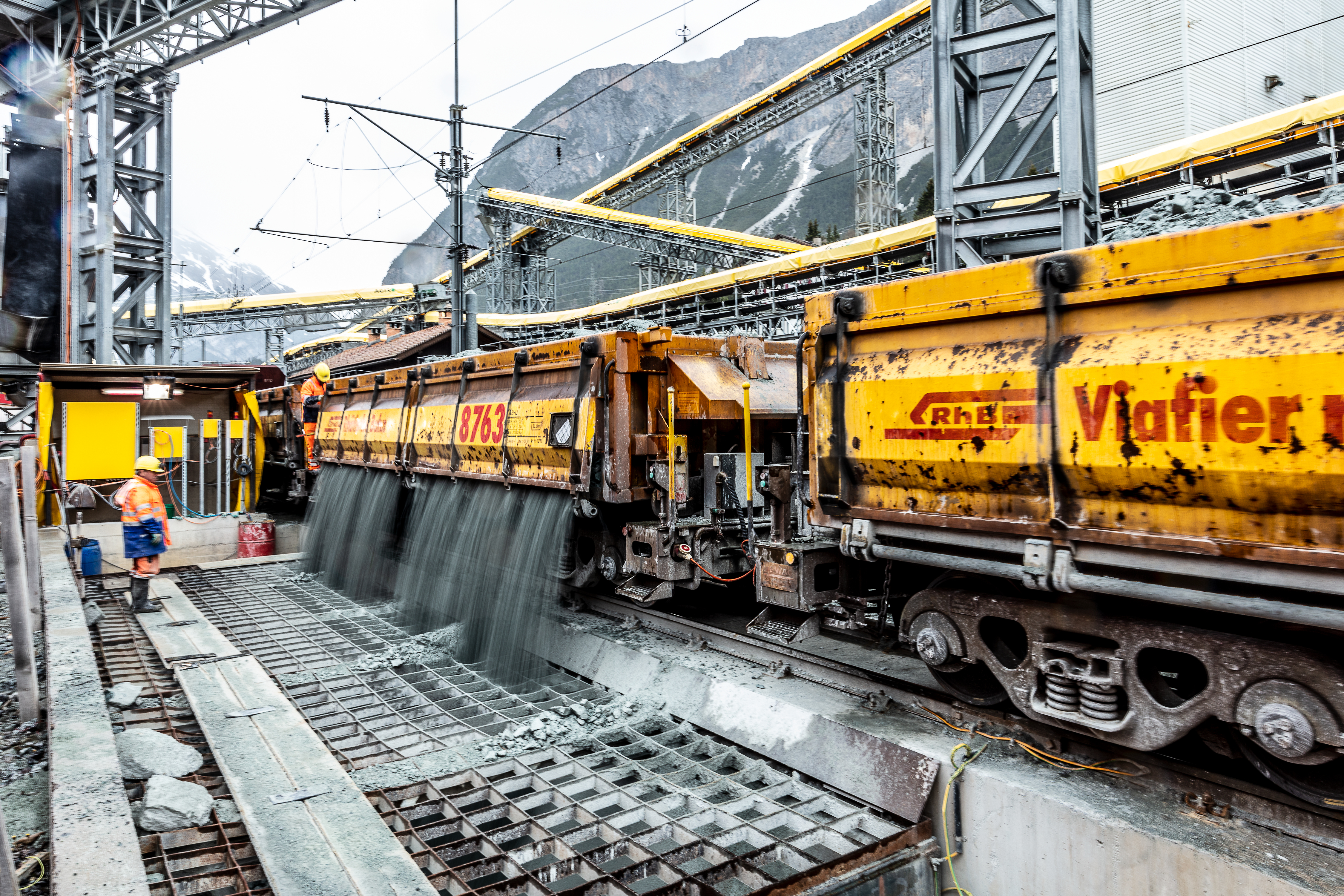 Ablad von Schüttgut von einem Schüttgut-Güterwagen beim Neubau des Albulatunnels auf einer Baustelle