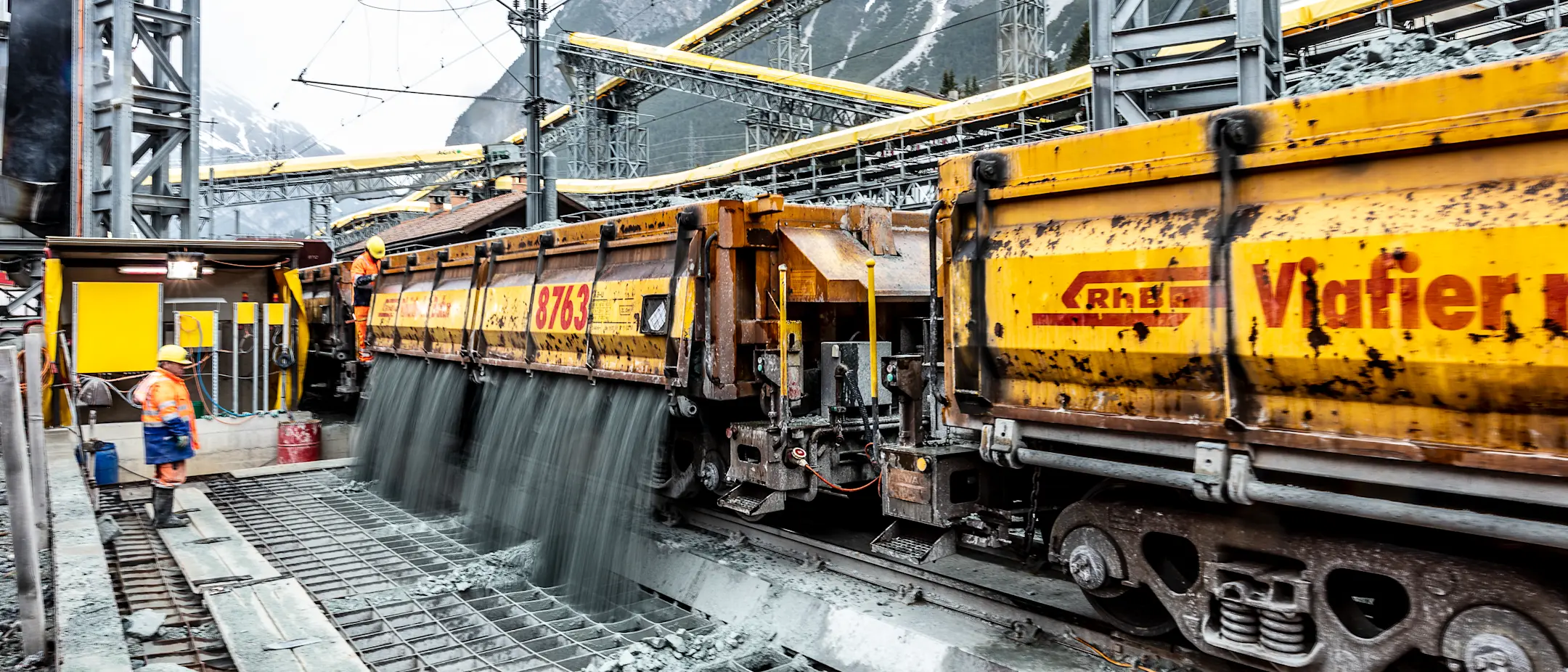 Ablad von Schüttgut von einem Schüttgut-Güterwagen beim Neubau des Albulatunnels auf einer Baustelle