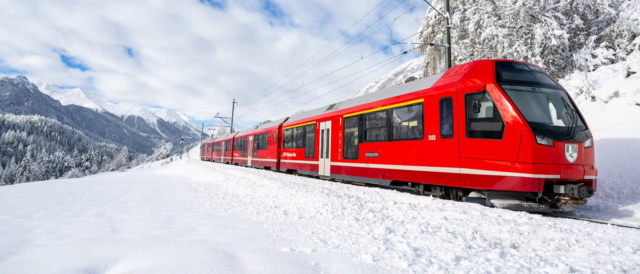 Ein Regionalzug der RhB im Engadin Winter, schneebedeckte Landschaft
