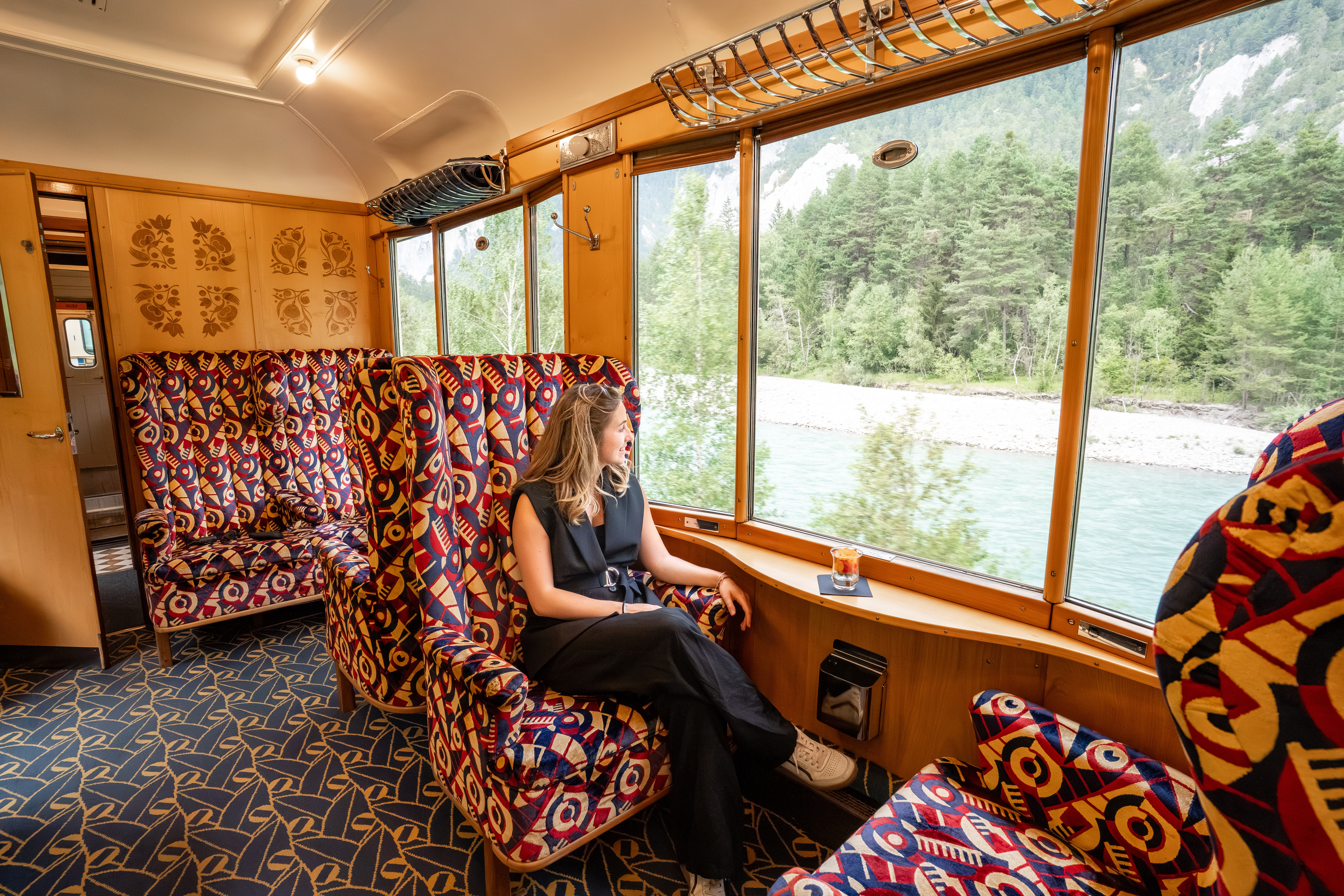 Ein Fahrgast sitzt vor dem Panorama im Alpine Classic Pullman Salonwagen