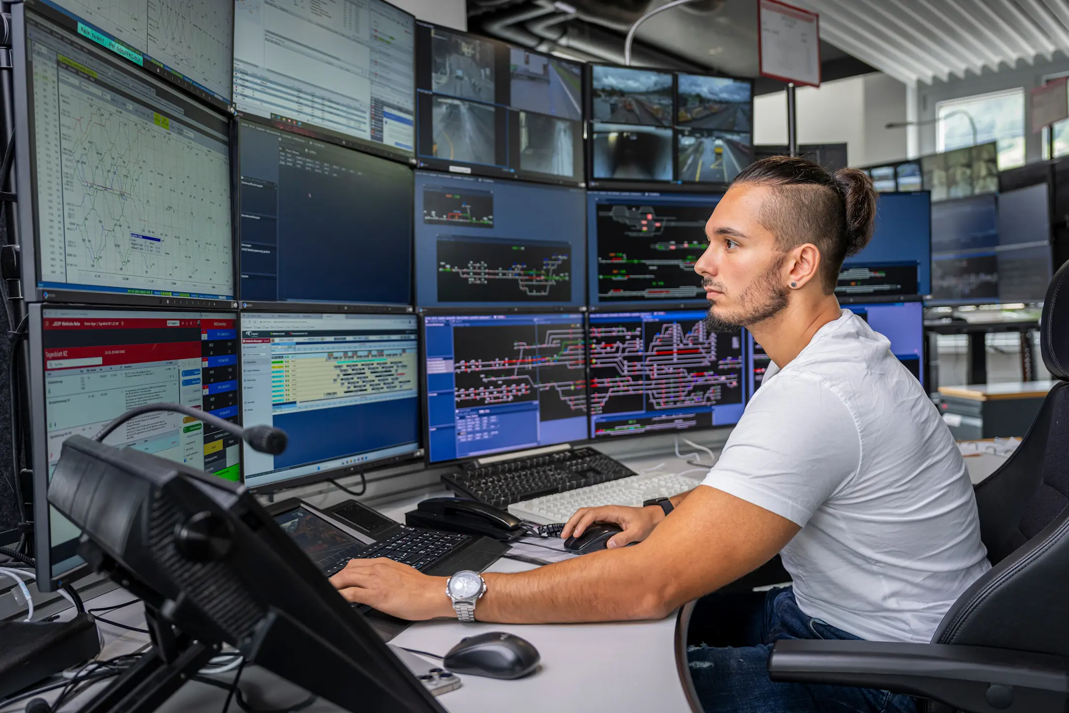 Ein Zugverkehrsleiter sitzt vor zahlreichen Monitoren bei der Arbeit