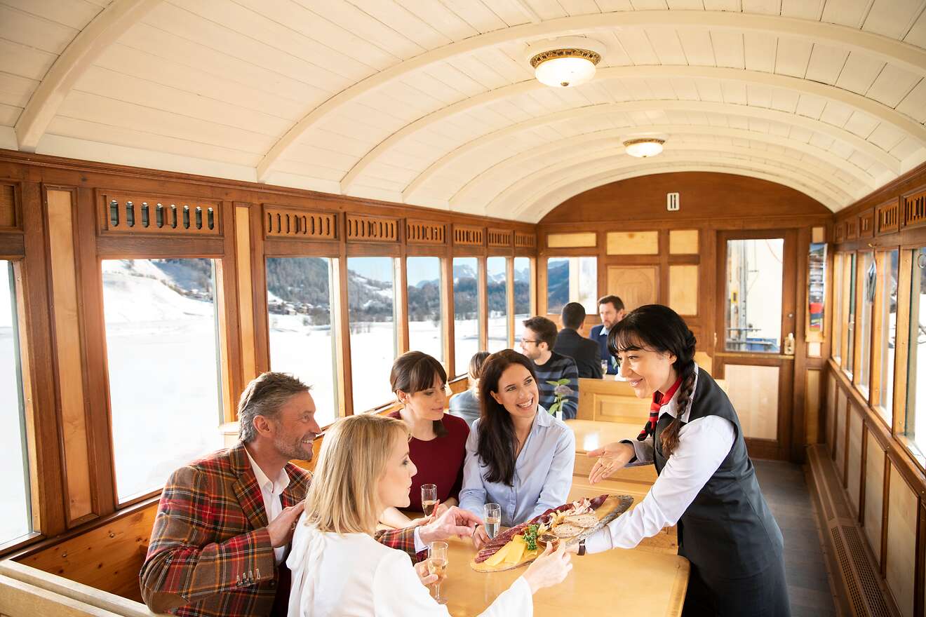 Mehrere Personen geniessen gemeinsam eine herzhafte Bündner Platte im holzverkleideten Filisurer Stübli.