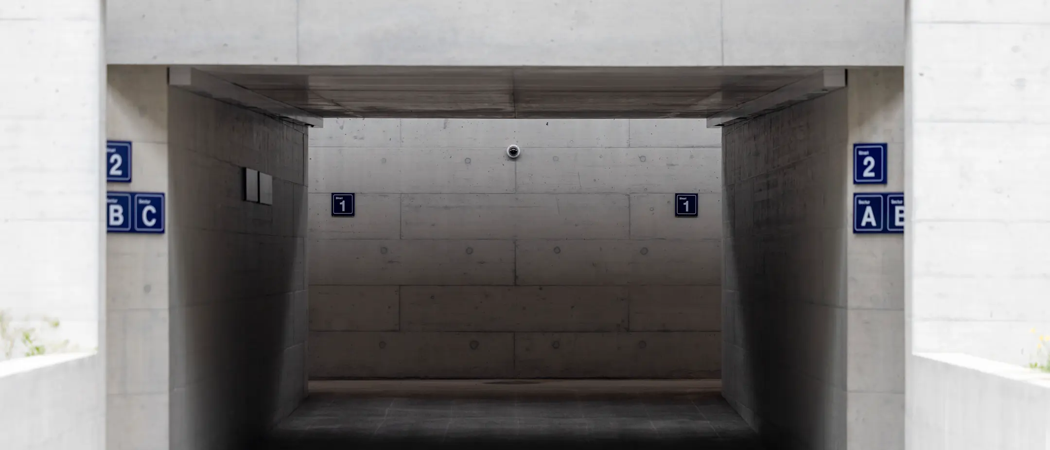 Unterführung am Bahnhof Trun mit Wegweisern zu den Gleisen, Videoüberwachung und Hinweisschildern.