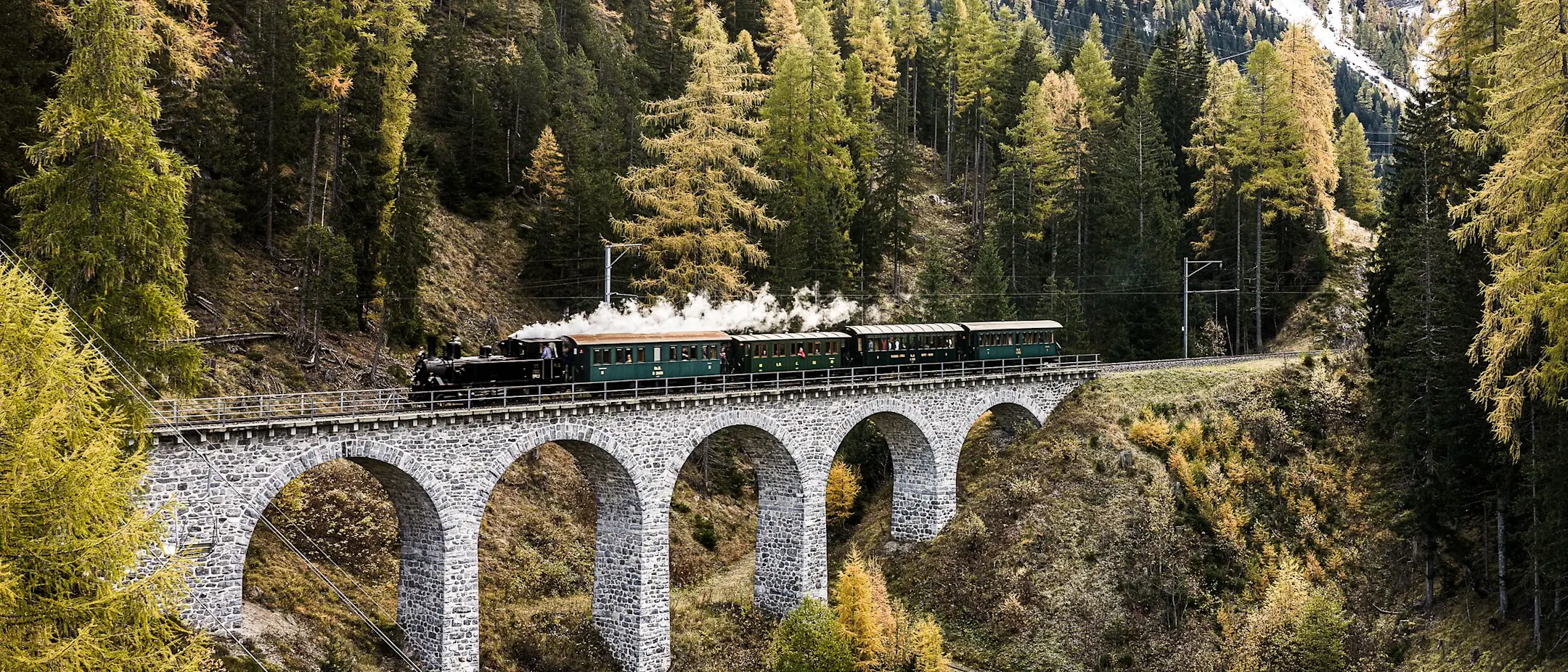 Ein Dampfzug der RhB Fährt über ein Viadukt im Albulatal.