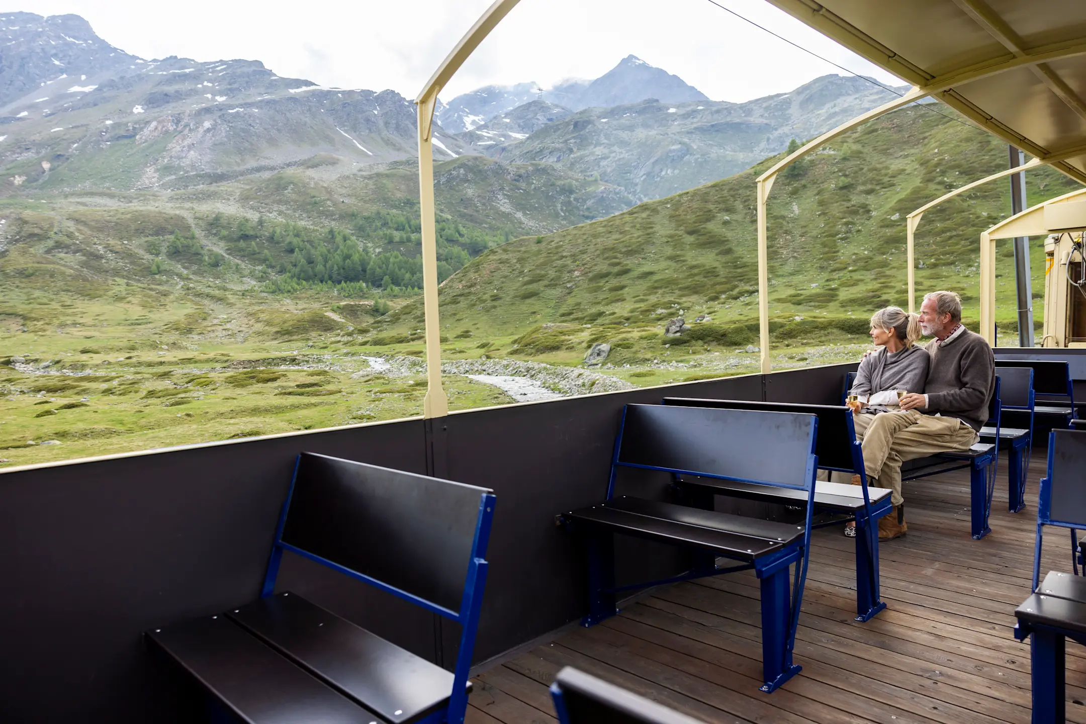 Cabrio Feeling: Ein Pärchen sitzt im offenen Aussichtswagen der Bernina Express Pullman Class.