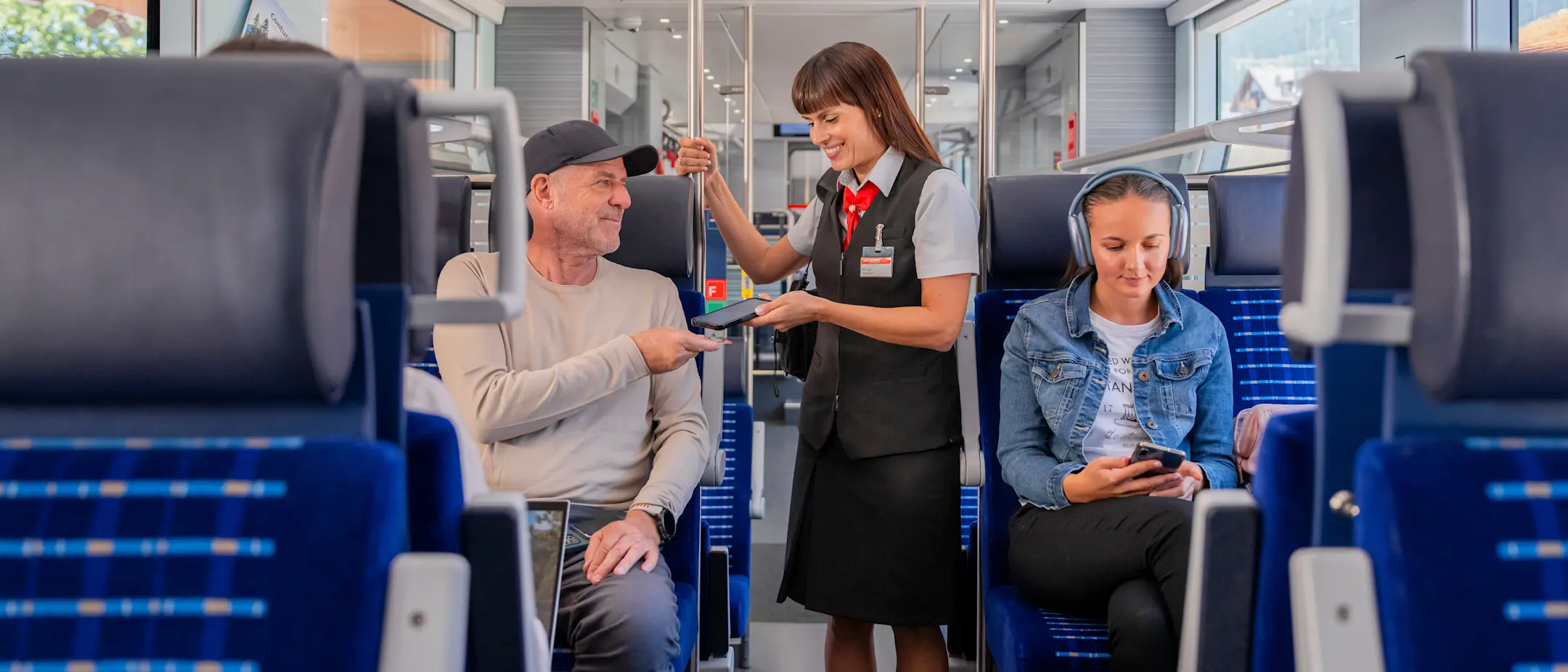 Eine Zugbegleiterin scannt im Zug das Ticket eines Fahrgastes