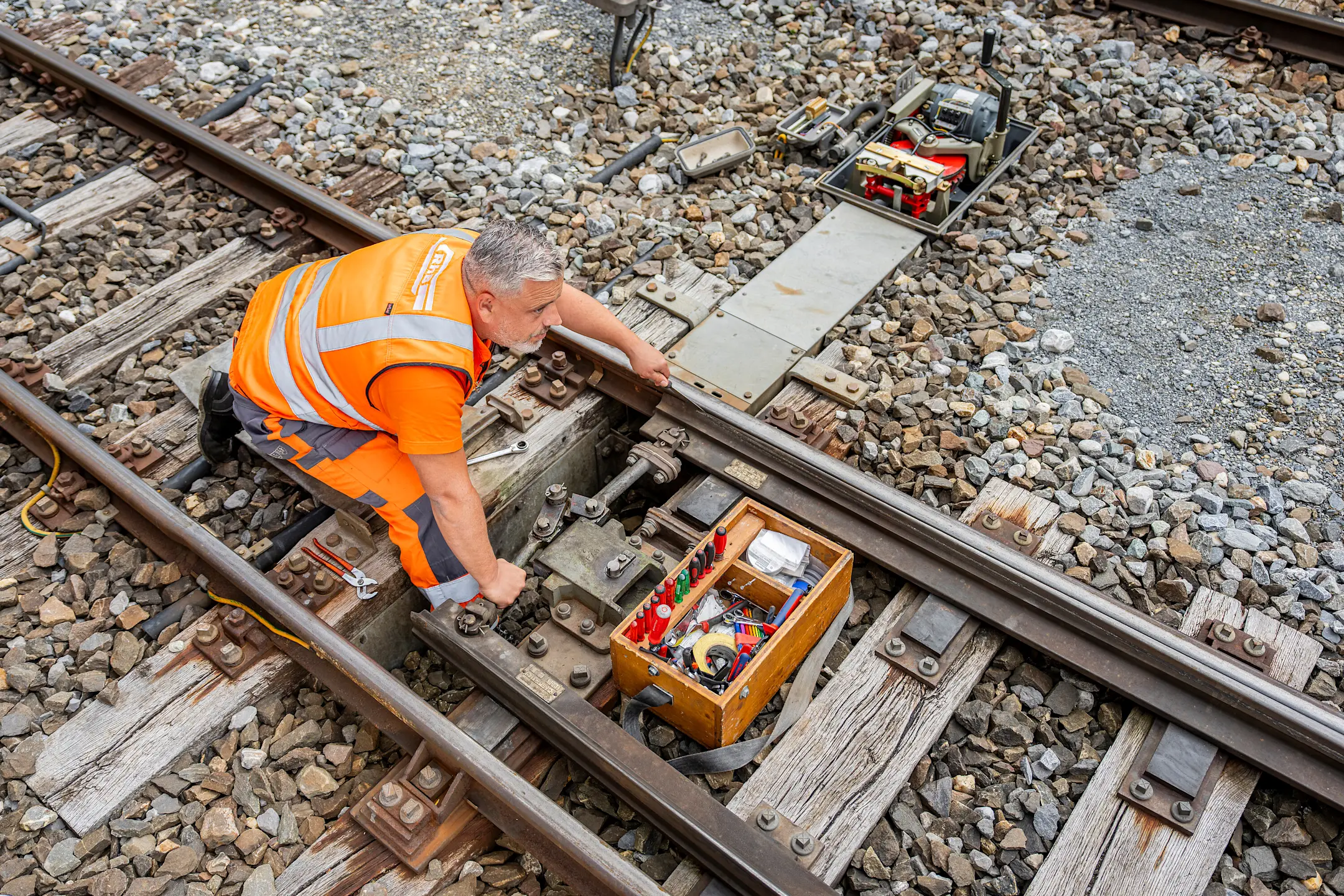Ein Elektroinstallateur bei der Arbeit im Gleisbett.