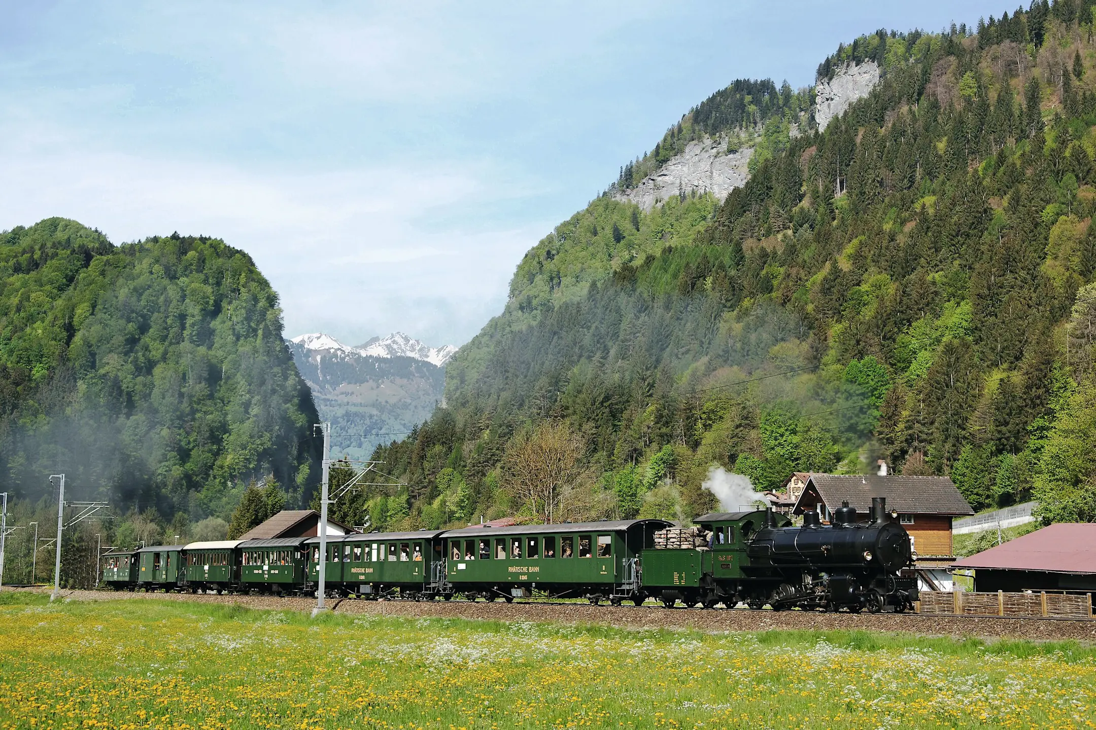 Ein historischer Dampfzug fährt bei Seewis im Prättigau durch die frühlingshafte Landschaft.