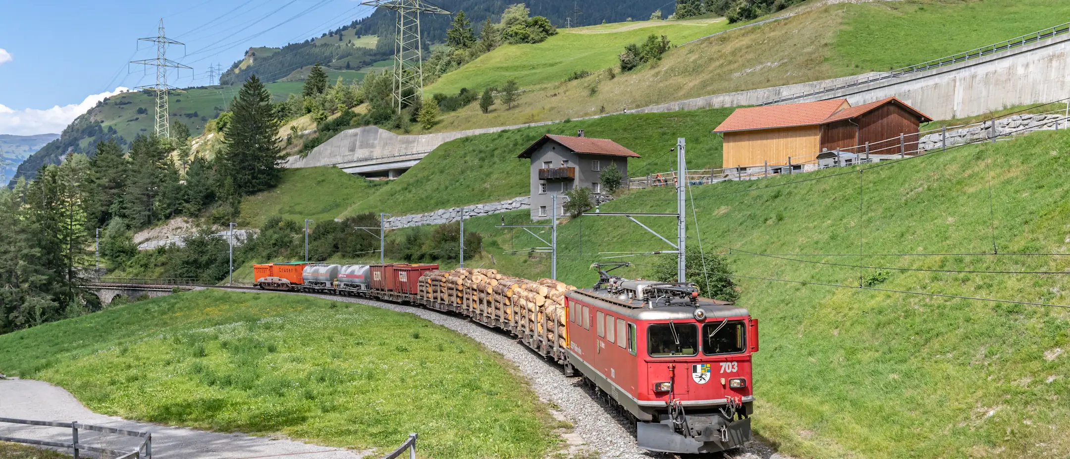 Ein Güterzug der Rhätischen Bahn fährt im Sommer durch das Albulatal für den Gütertransport in Graubünden