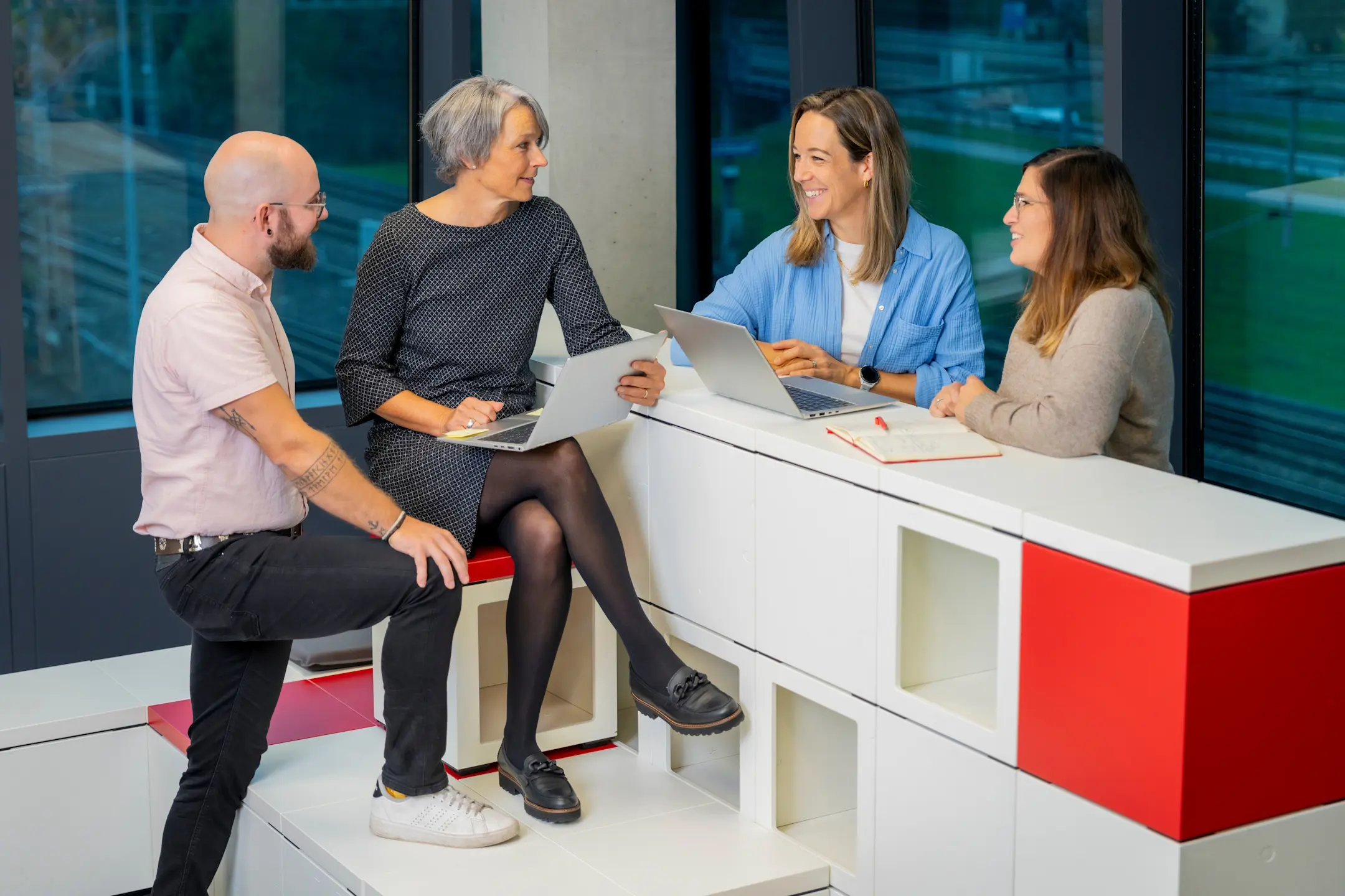 3 Mitarbeiterinnen und 1 Mitarbeiter an einer Besprechung an einer Theke