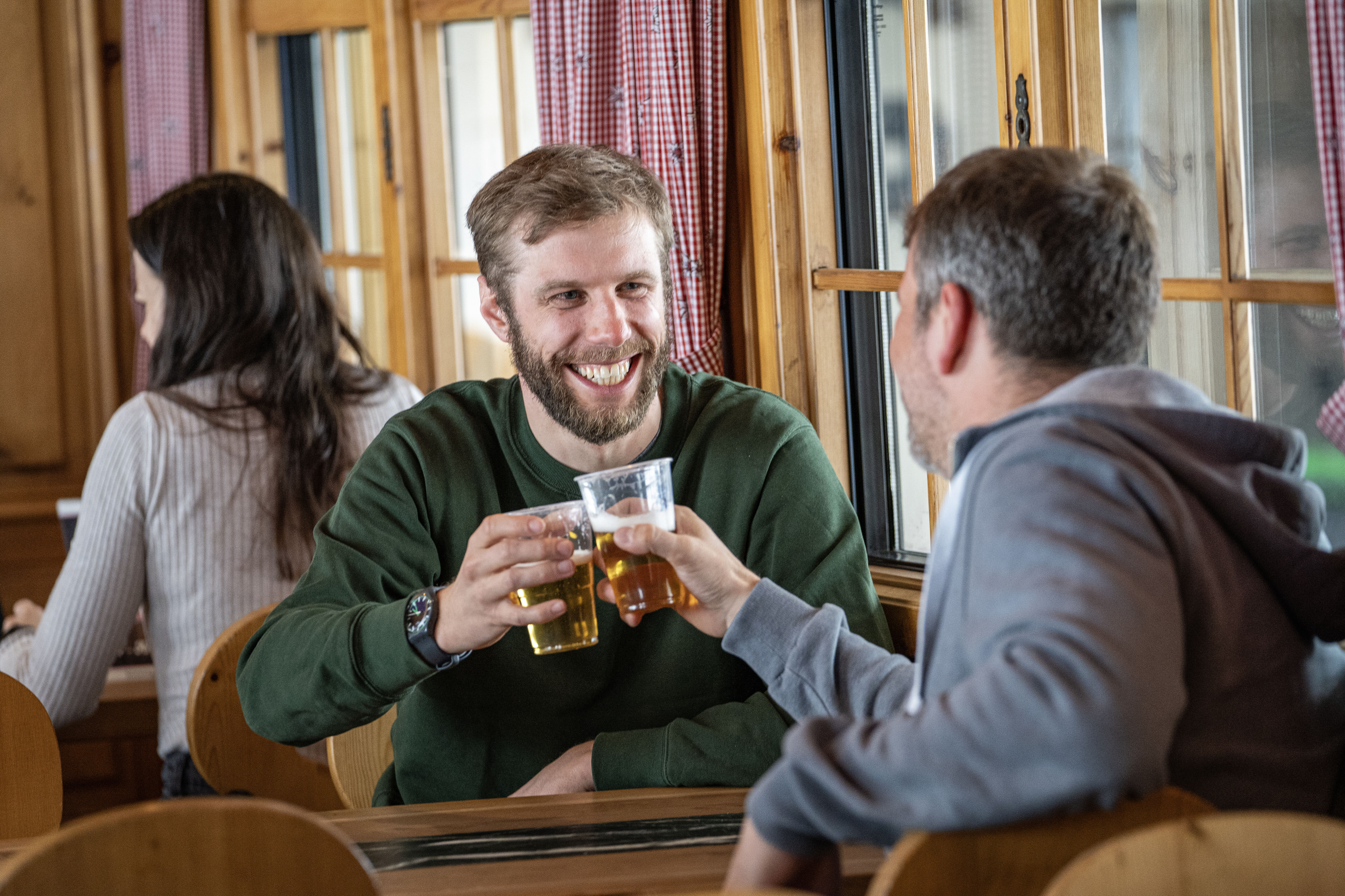 Two men in the Stiva Retica clink beer glasses.