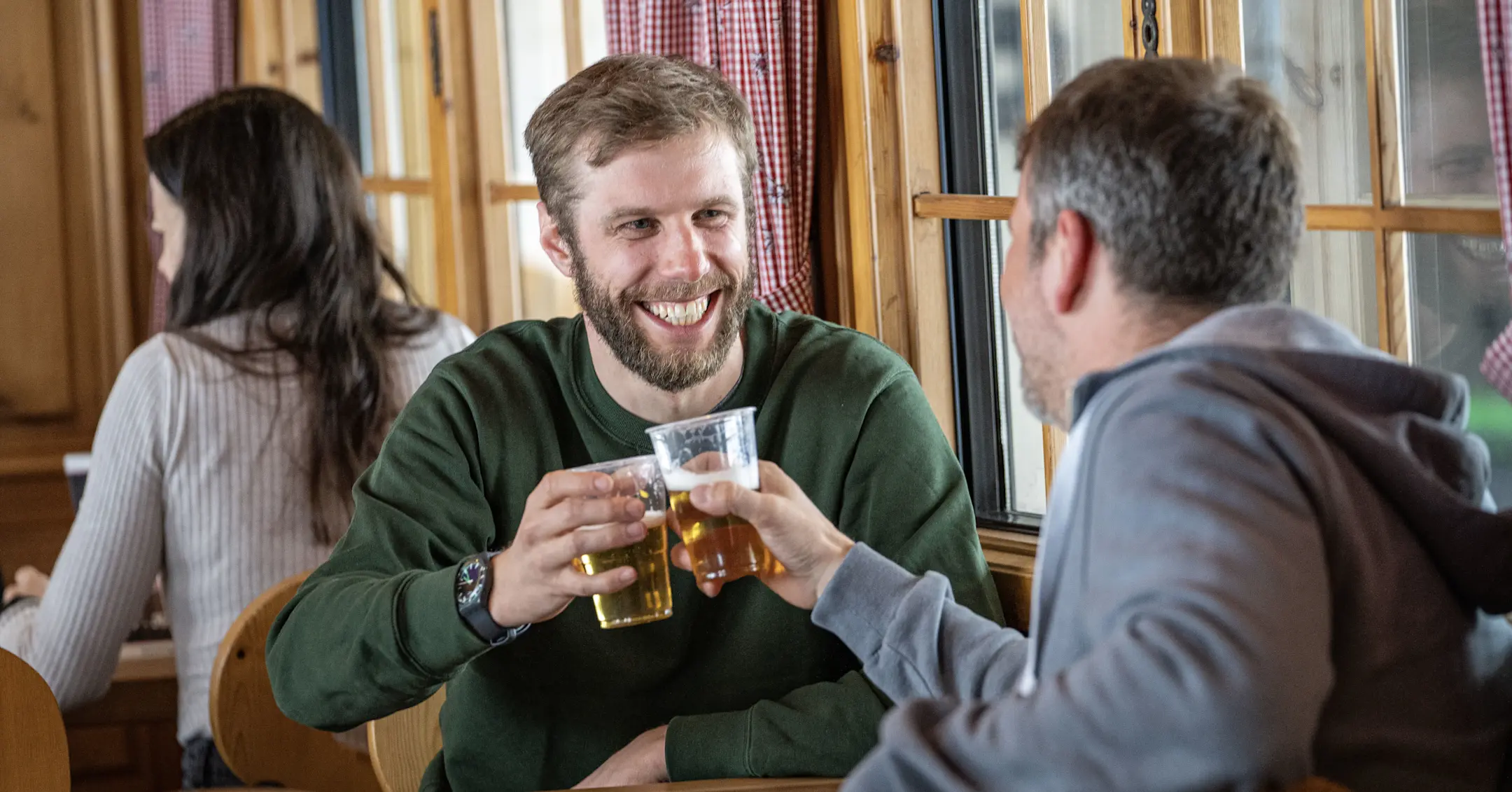 Zwei Männer stossen in der Stiva Retica mit Bier an.