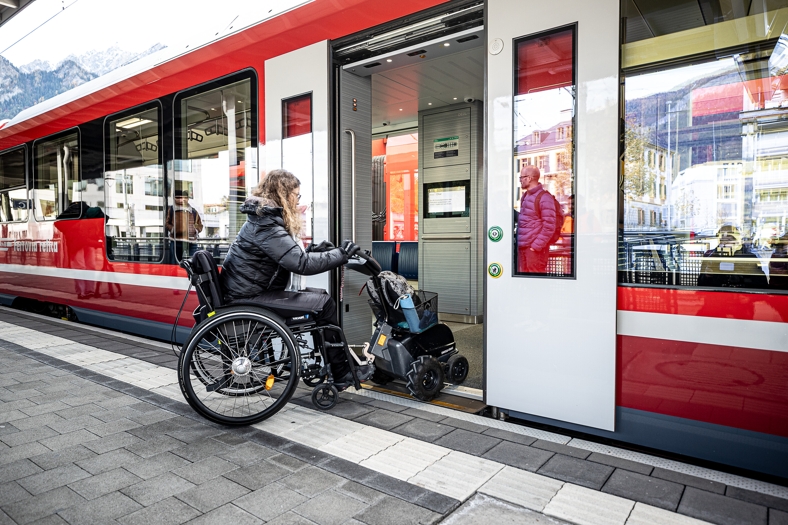 Frau mit Rollstuhl fährt über den Schiebetritt hinein in den Capricorn-Triebzug