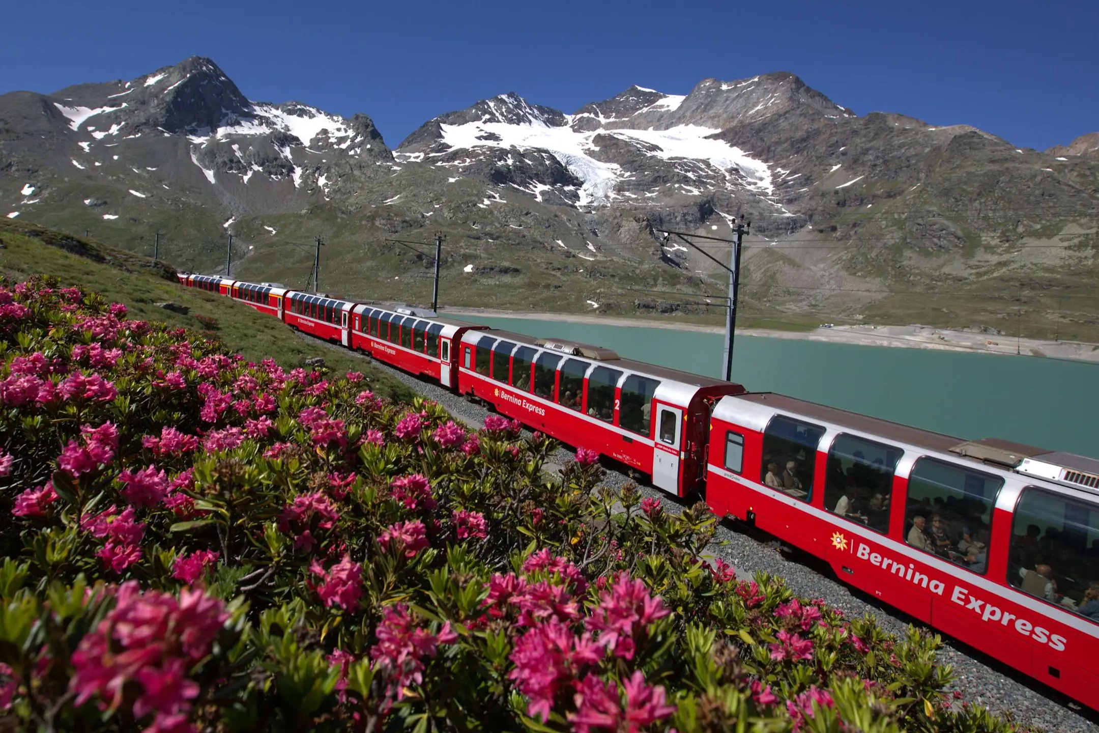 Der Bernina Express fährt durch malerische Landschaft am Lago Bianco.