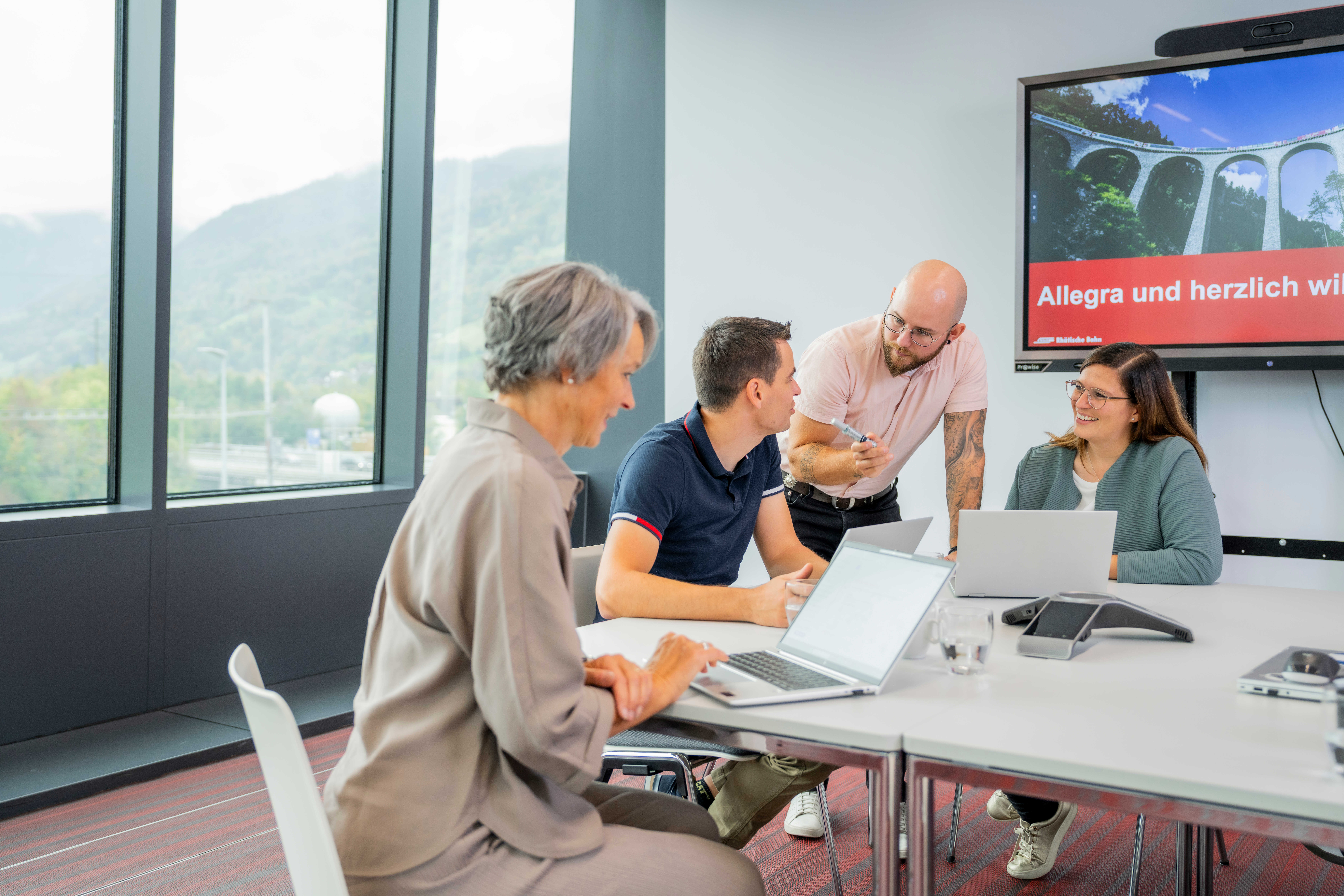 4 collaboratori seduti attorno a un tavolo durante una riunione con i loro computer portatili
