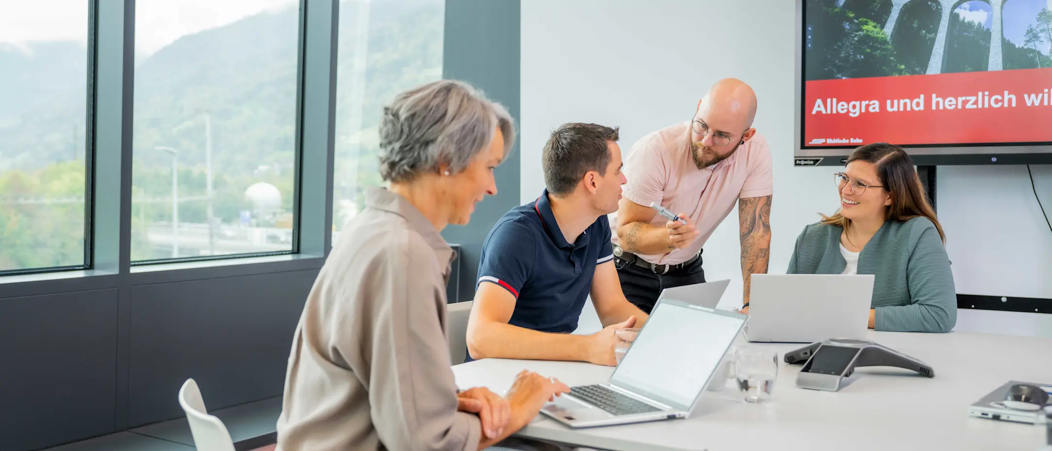 4 collaboratori seduti attorno a un tavolo durante una riunione con i loro computer portatili
