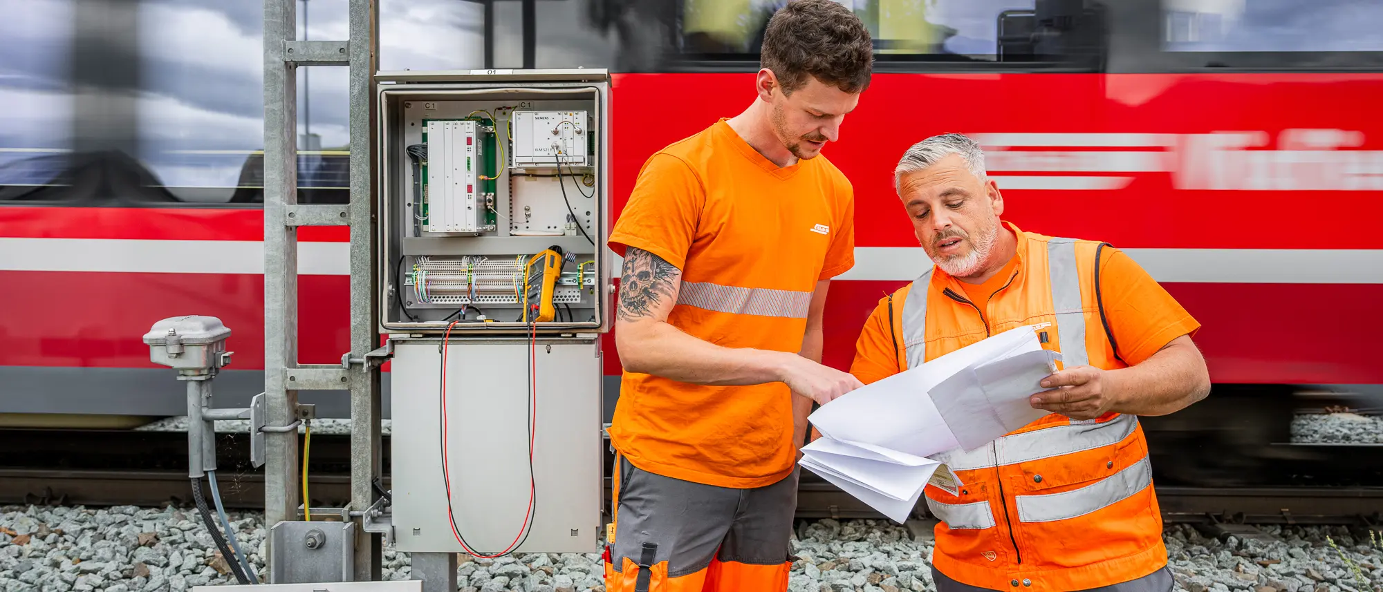 Two electricians talking – a train rushes past in the background