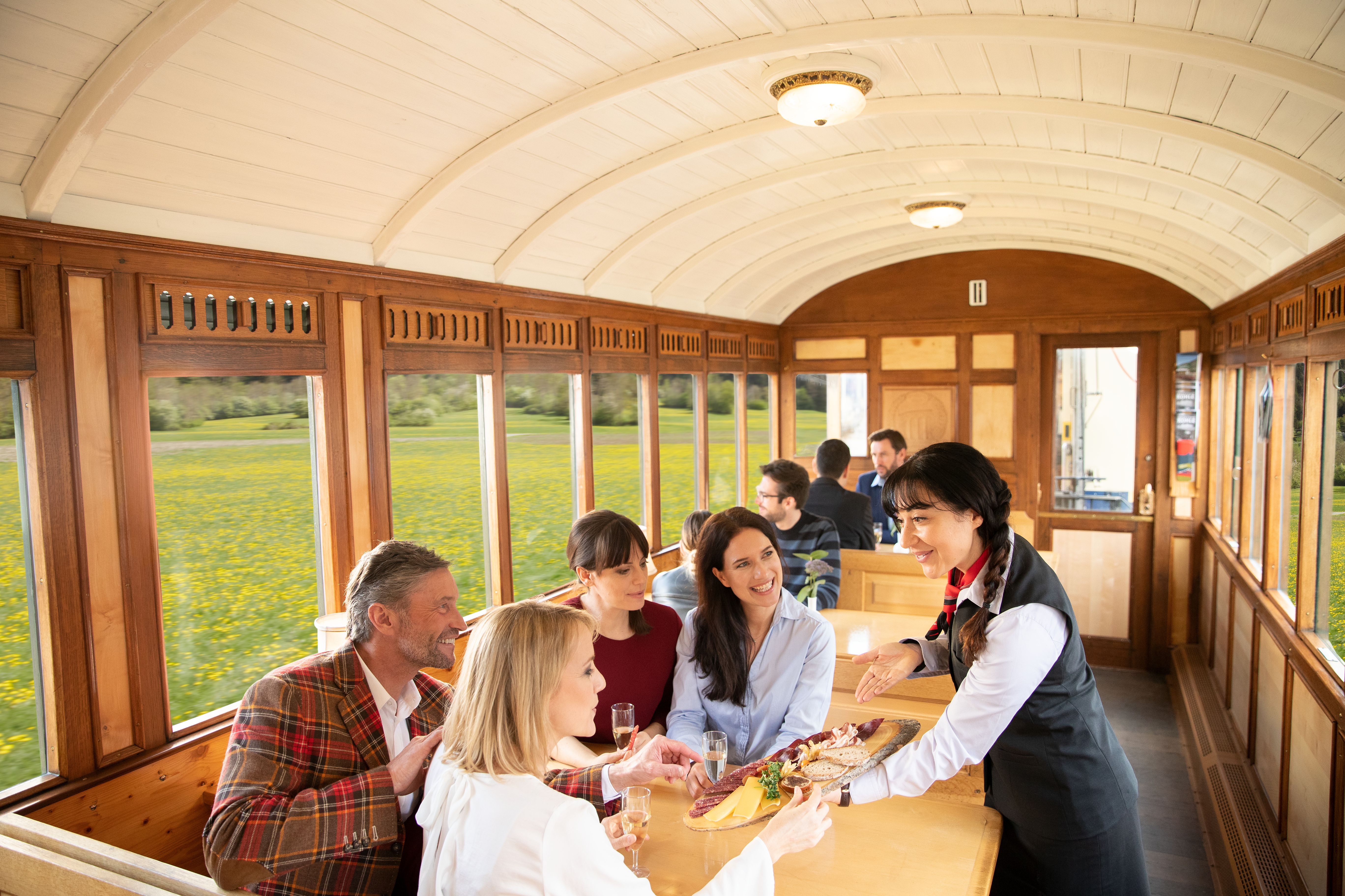Im Filisurer Stübli serviert eine RhB-Servicemitarbeiterin vier Fahrgästen Verpflegung.