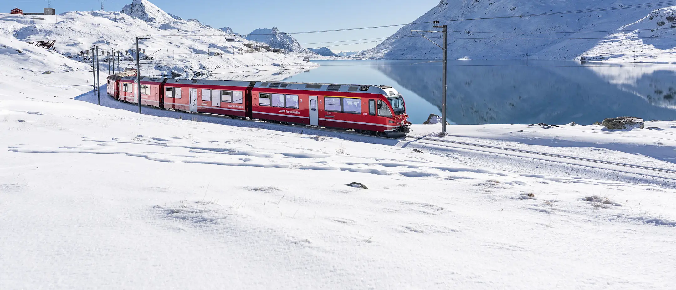 Un treno regionale della FR costeggia il Lago Bianco lungo la Linea del Bernina.