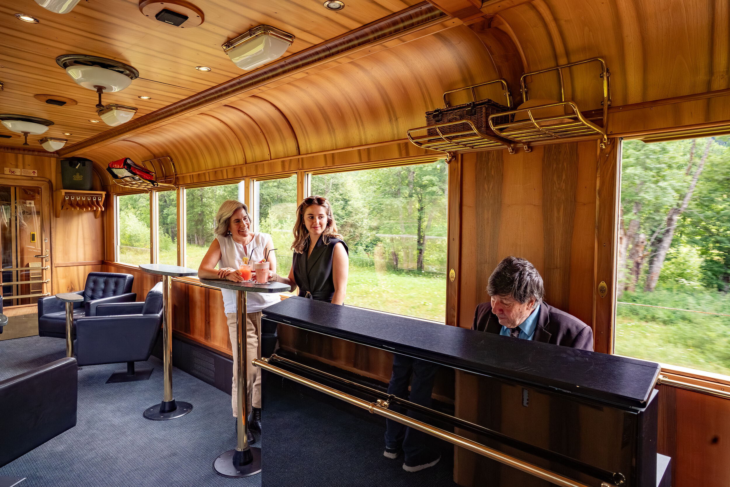 Der Piano Bar Waggon der Rhätischen Bahn, ein Pianist spielt am Piano, im Hintergrund Fahrgäste.
