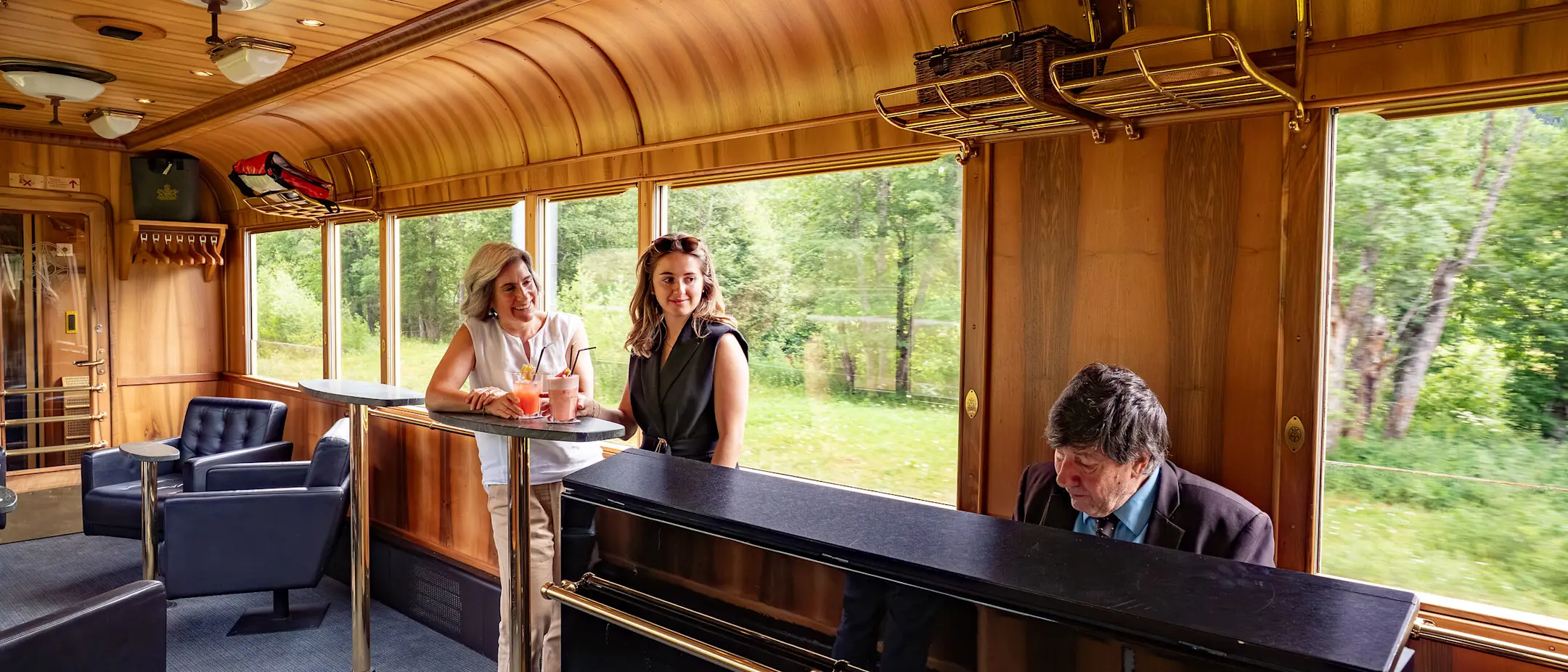 Der Piano Bar Waggon der Rhätischen Bahn, ein Pianist spielt am Piano, im Hintergrund Fahrgäste.